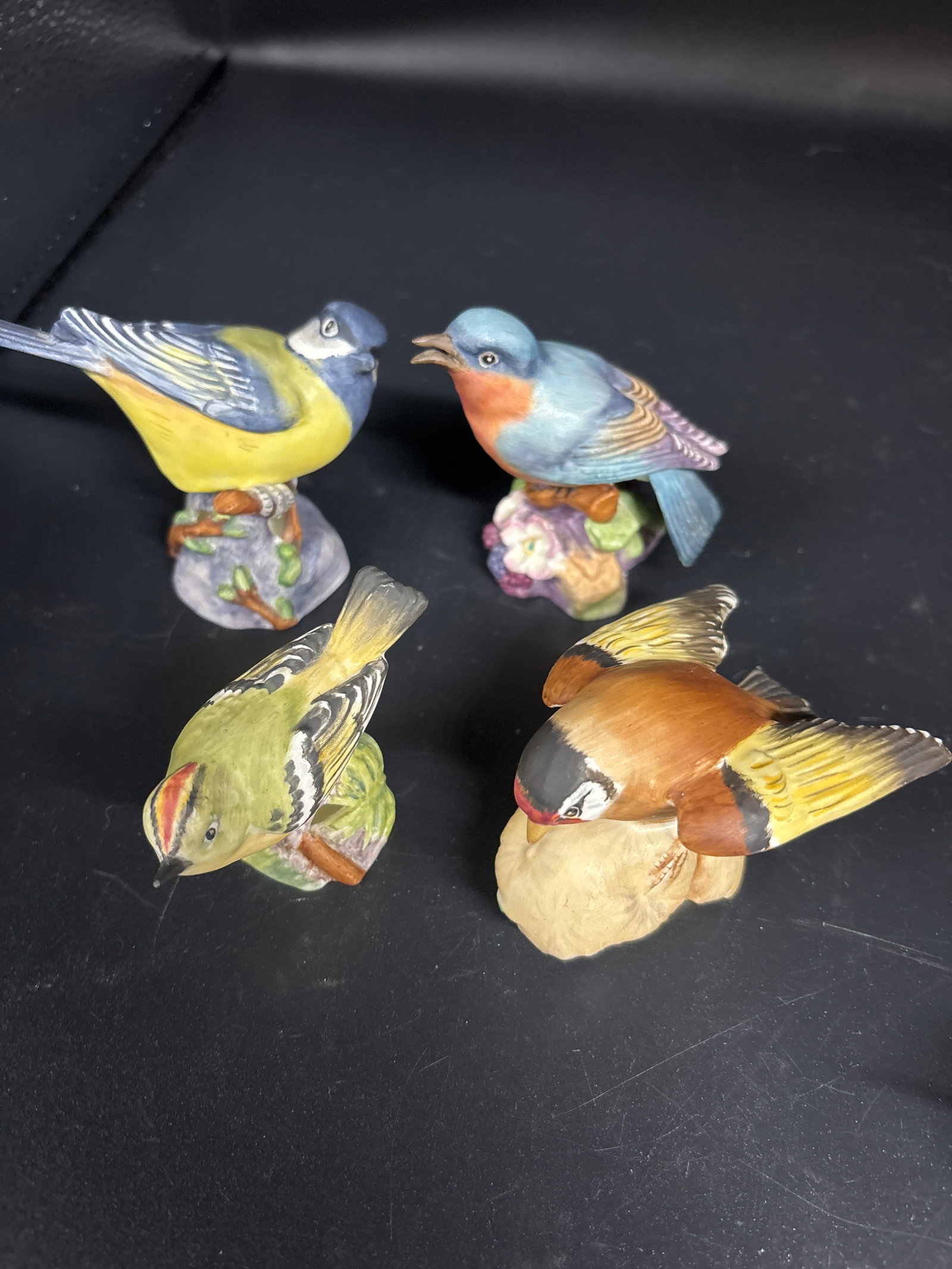 Four Royal Worcester bird sculptures, hand made from fine English bone china: Four Royal Worcester bird sculptures, hand made from fine bone china in England.The model, specifically identified as a Blue Tit, Blue Bird, Gold Crest & Goldfinch, often features intricate, hand-pain