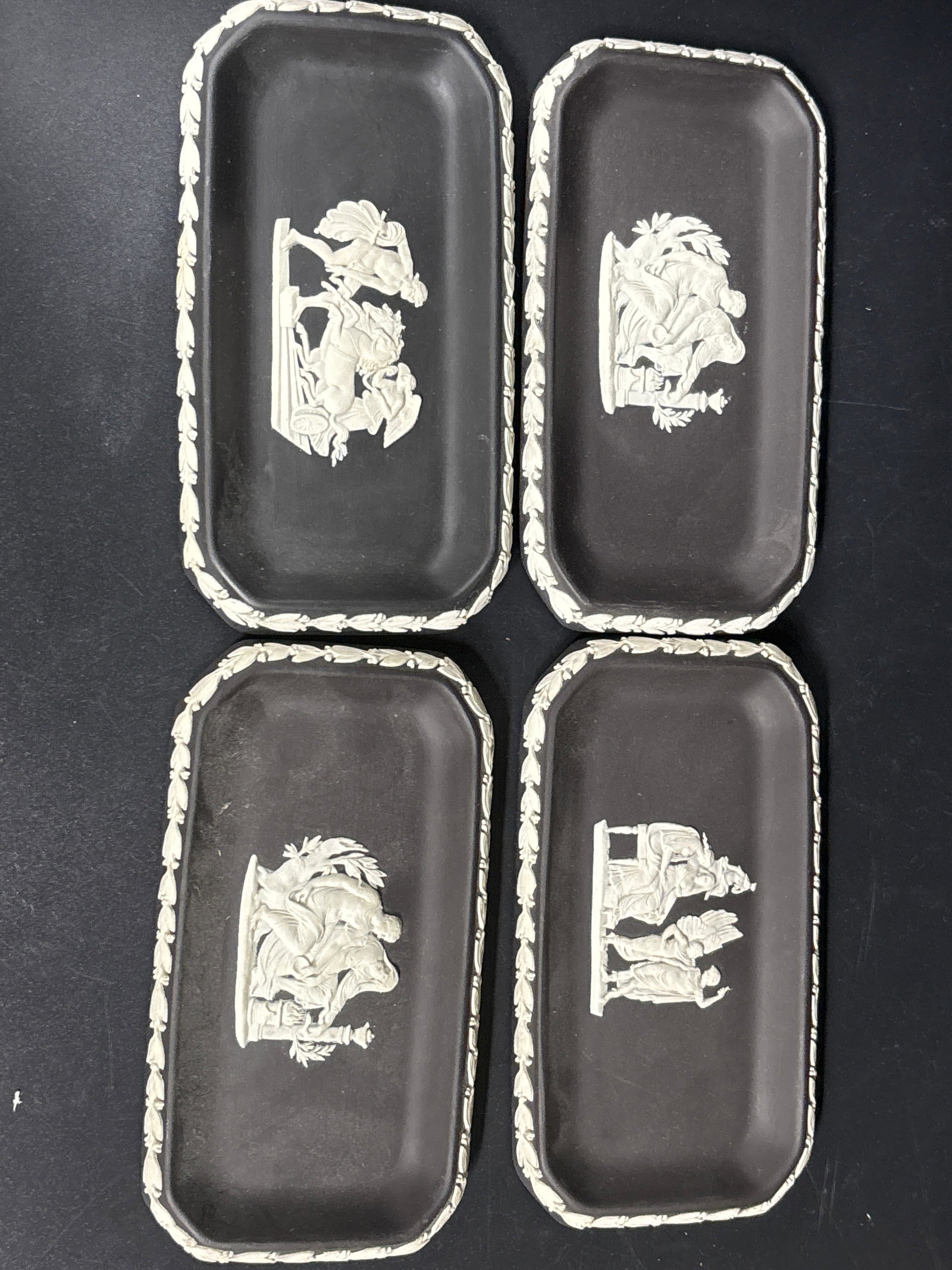 Set of four Wedgwood Jasperware jewelry dishes in black basalt with white: Set of four Wedgwood Jasperware jewelry dishes in black basalt with white neoclassical figures, often referred to as pin or trinket trays.They typically measure approximately 5 3/4" by 3 1/4".These