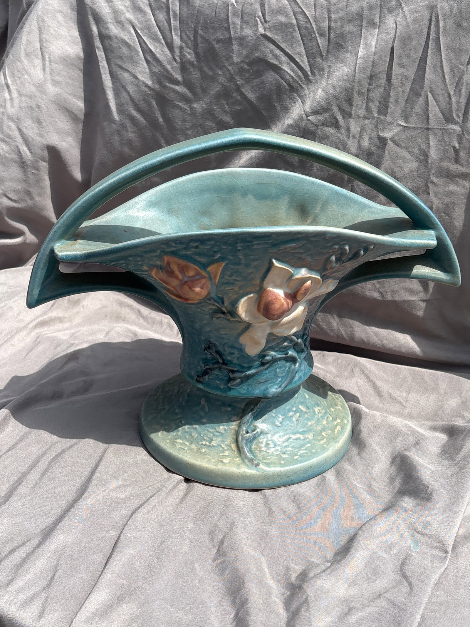 vintage Roseville art pottery 10x12 inch basket from the Magnolia line: vintage Roseville art pottery basket from the Magnolia line, featuring a blue glazed finish with molded pink and white flowers.Model Number: 385-10, indicating it is the 10-inch version of this design