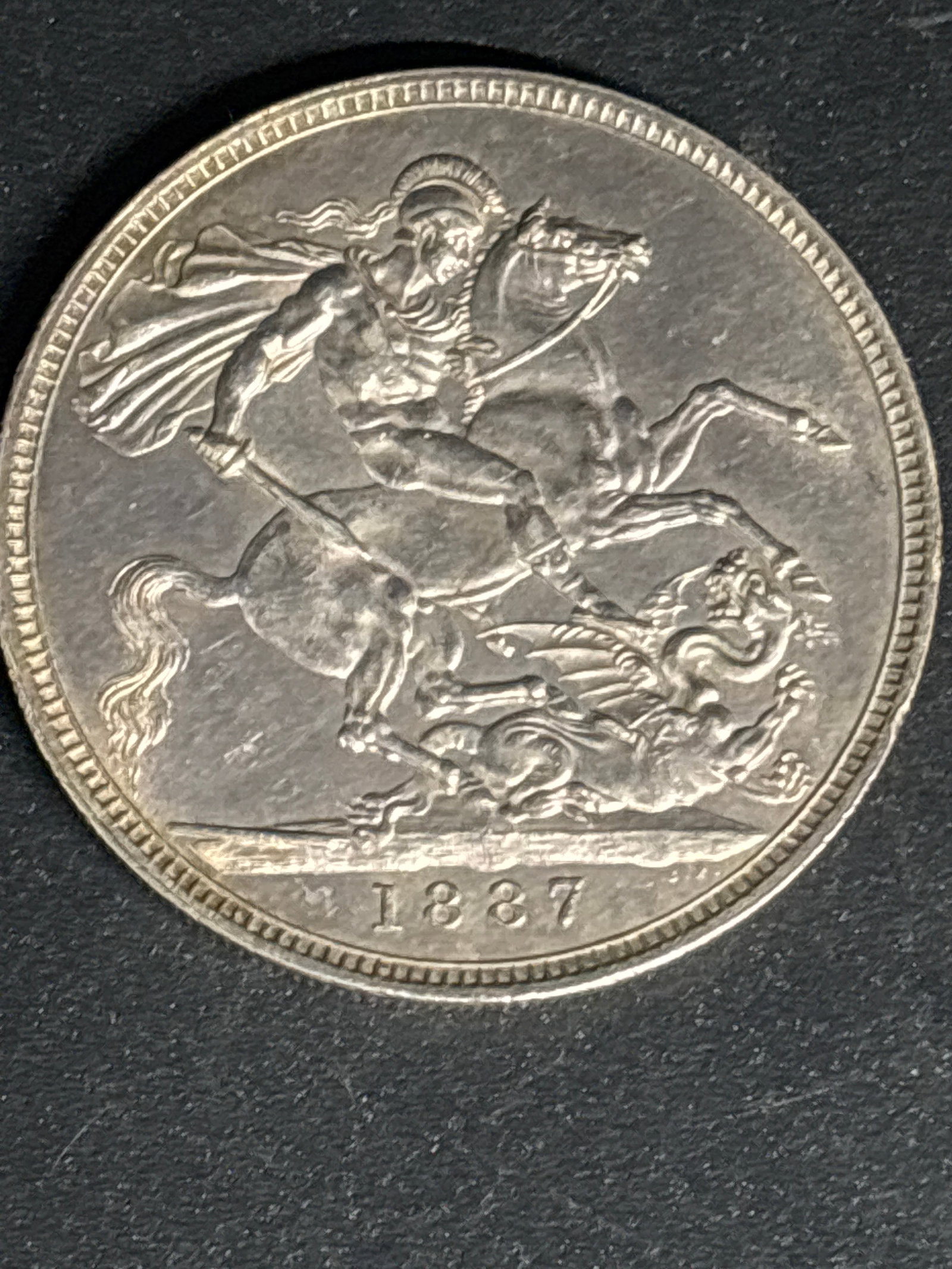28.28 grams .925 Silver Queen Victoria era British 1887 Silver Crown: British 1887 Silver Crown minted during the reign of Queen Victoria.Key Details & IdentificationReverse Design: Features the iconic depiction of St. George slaying the dragon, designed by Benedetto Pi