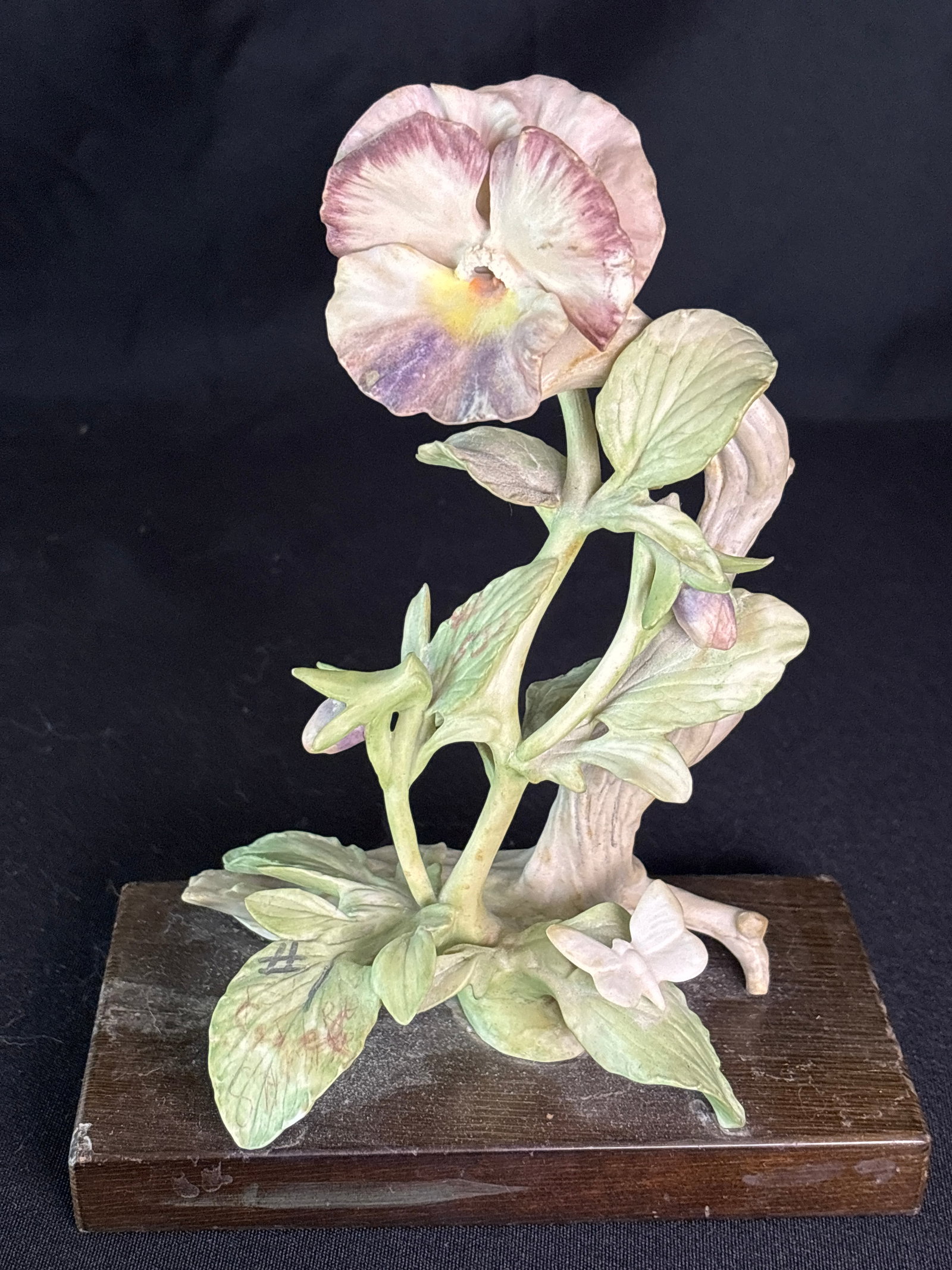 Cybis porcelain pansy figurine with a butterfly: Cybis porcelain pansy figurine with a butterfly.The piece is mounted on a wooden base.It is likely part of the Cybis flower study collection, which produced various studies of flowers throughout its