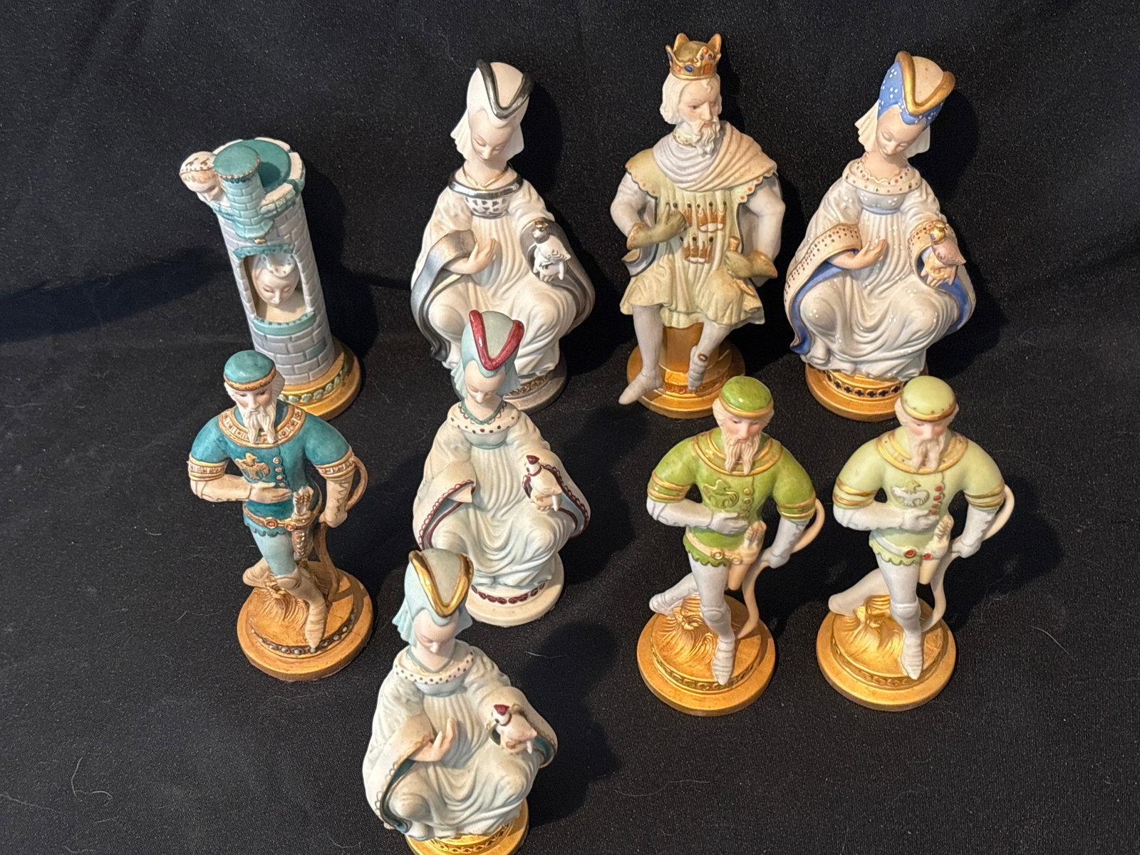 Green/blur nine piece similar unsigned Cybis white porcelain chess figures: Nine piece similar Cybis white porcelain figures arranged in rows, including three pawns holding bows, four various queen including a silver one, one king, one rook formatted as an ornate castle tower