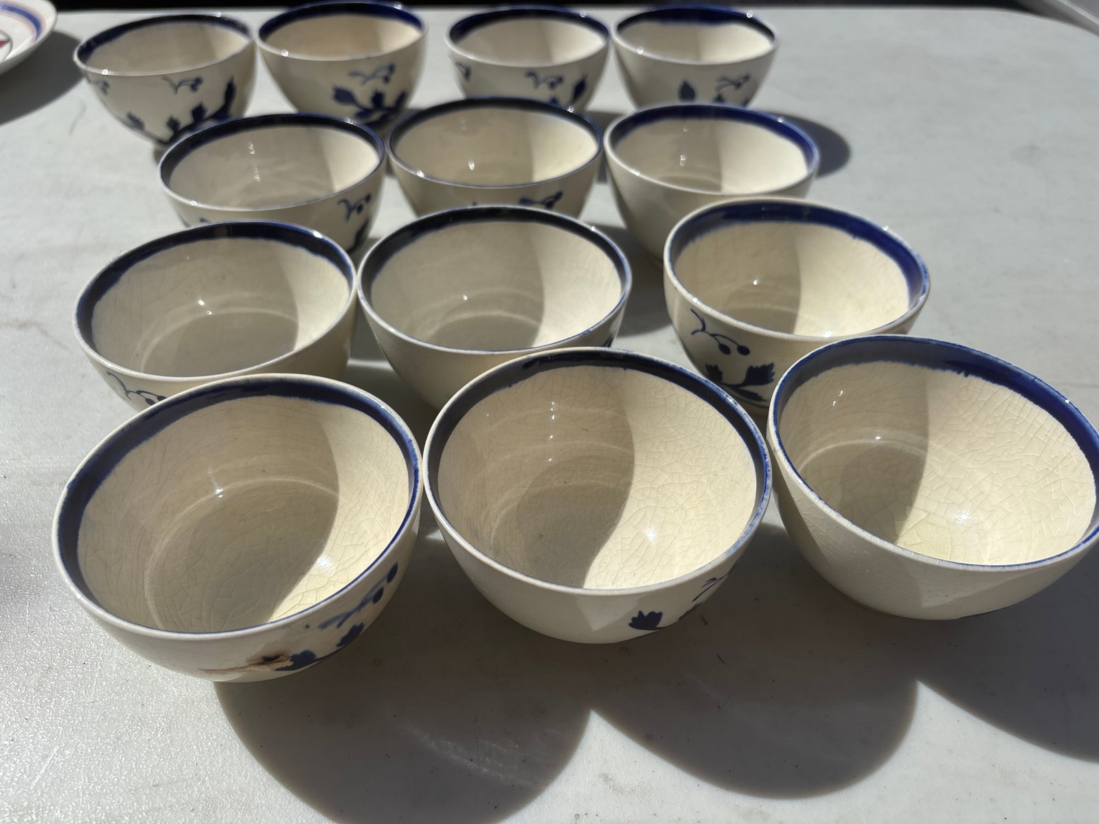 Thirteen unsigned Cybis blue and white hand-painted ceramic handless cups: Thirteen unsigned Cybis blue and white hand-painted ceramic cuos which feature prominent cobalt brush strokes depicting leaves, vines, and whimsical accents.While Cybis is primarily world-renowned for
