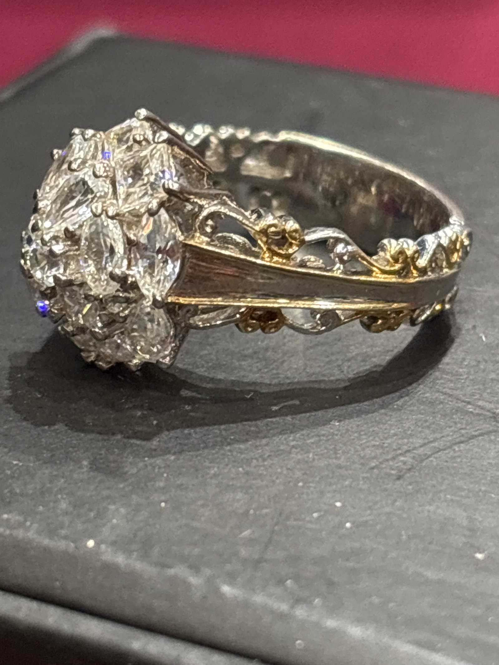 .925 Silver floral cluster ring set with two-tone gold tone accents: Large floral cluster ring features a detailed diamond or cubic zirconia arrangement set in two-tone gold.Design: A flower-shaped cluster design featuring a central stone surrounded by smaller pear or 