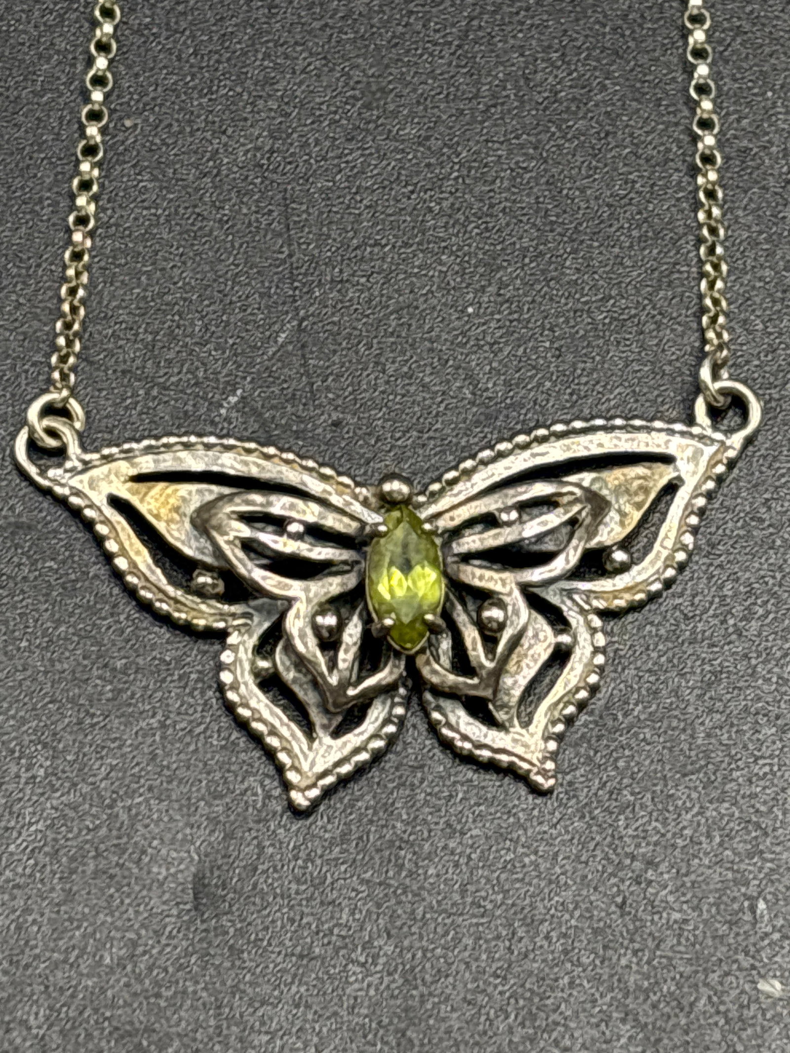 Israel sterling silver butterfly necklace featuring a marquise-cut peridot stone: Israel sterling silver butterfly necklace featuring a marquise-cut peridot stone at its center. Peridot serves as the traditional birthstone for August. The pendant features detailed, cut-out filigree
