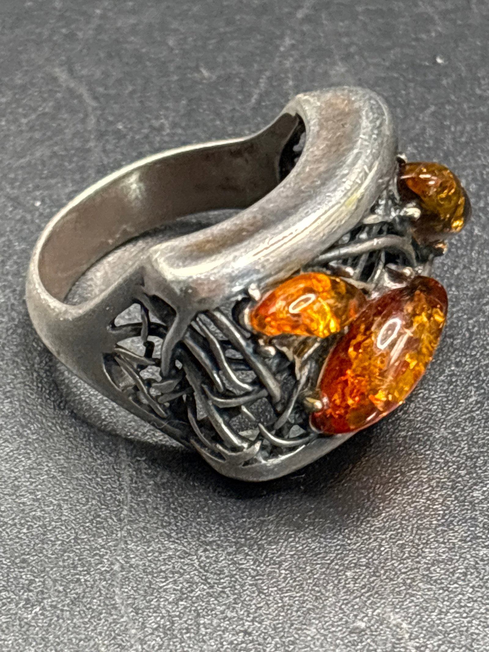 sterling silver ring features three Baltic amber stones set within a delicate filigree: sterling silver ring features three Baltic amber stones set within a delicate filigree design.Material: 925 Sterling Silver.Stones: Baltic amber in honey and cognac colors.Design: Intricate filigree