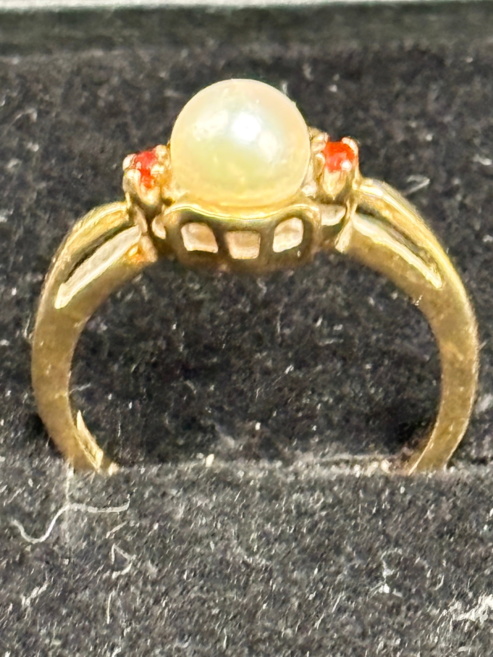 2.86 grams 9k gold ring central white cultured pearl: 2.86 grams vintage 9k gold vintage yellow gold ring styled with a central white cultured pearl accented by two small red gemstones (likely rubies or garnets) nestled into the shoulders.Metal Purity In