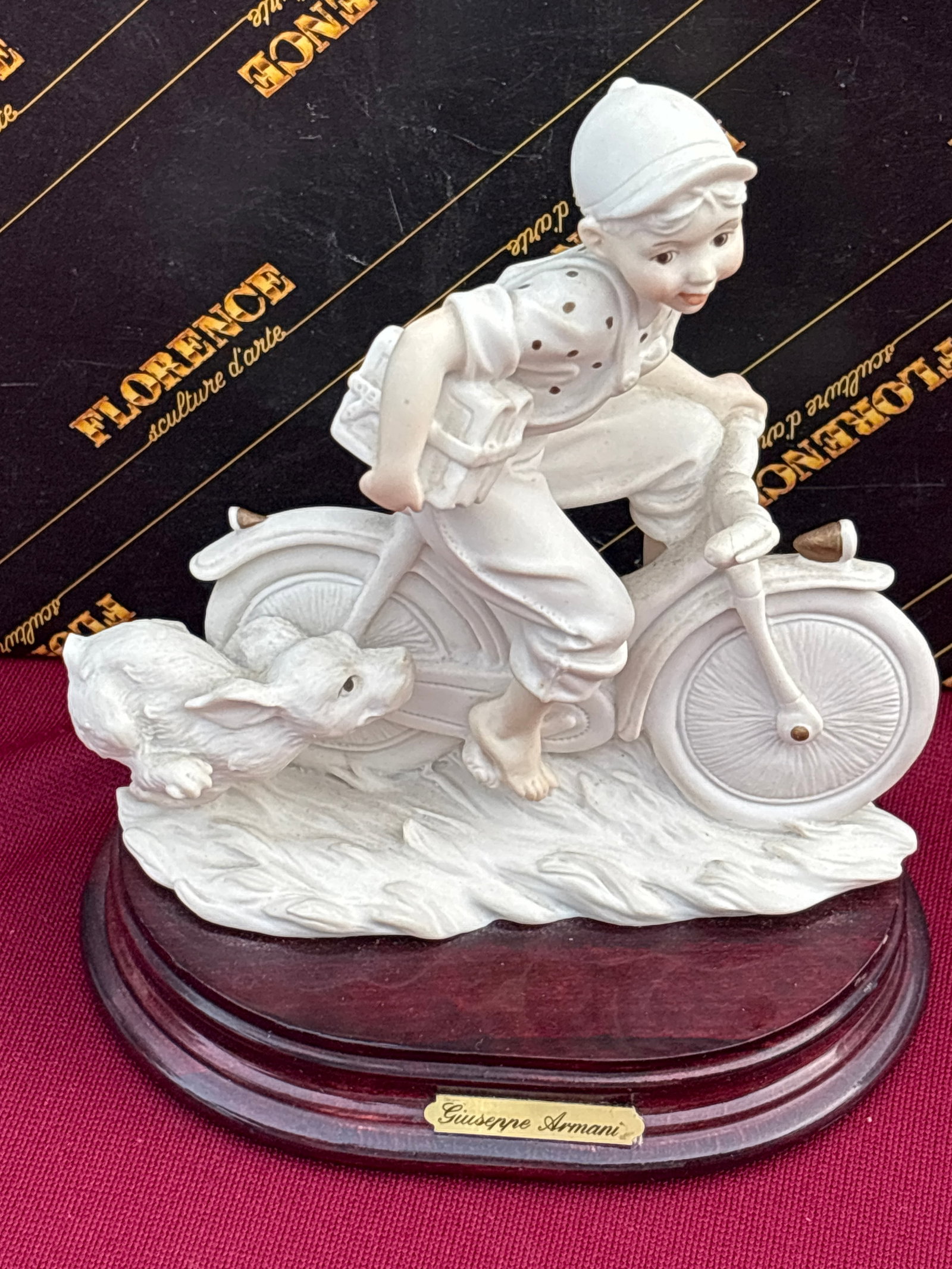 Giuseppe Armani "Florence" collection sculpture, titled "Late to School" boy on bike: Giuseppe Armani "Florence" collection sculpture, titled "Late to School" or featuring a boy on a bicycle with a dog.It is crafted from resin or porcelain and is mounted on a wooden base with a namepla