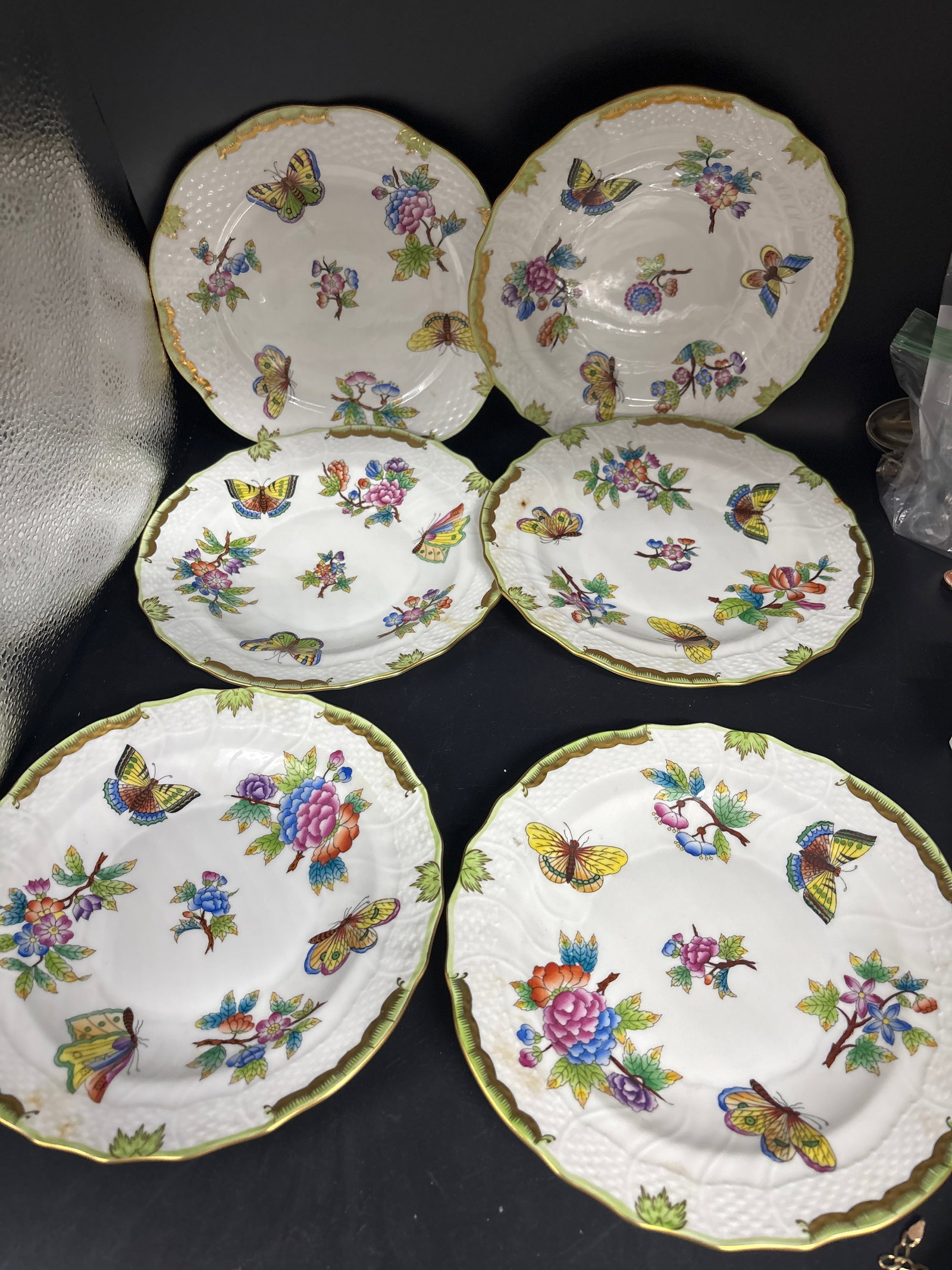 Set of six Herend porcelain plates in the Queen Victoria pattern: Set of six Herend porcelain plates in the Queen Victoria pattern, featuring a signature hand-painted butterfly and flower motif with gold accents.Brand: Herend, manufactured in Hungary.Pattern: Queen 