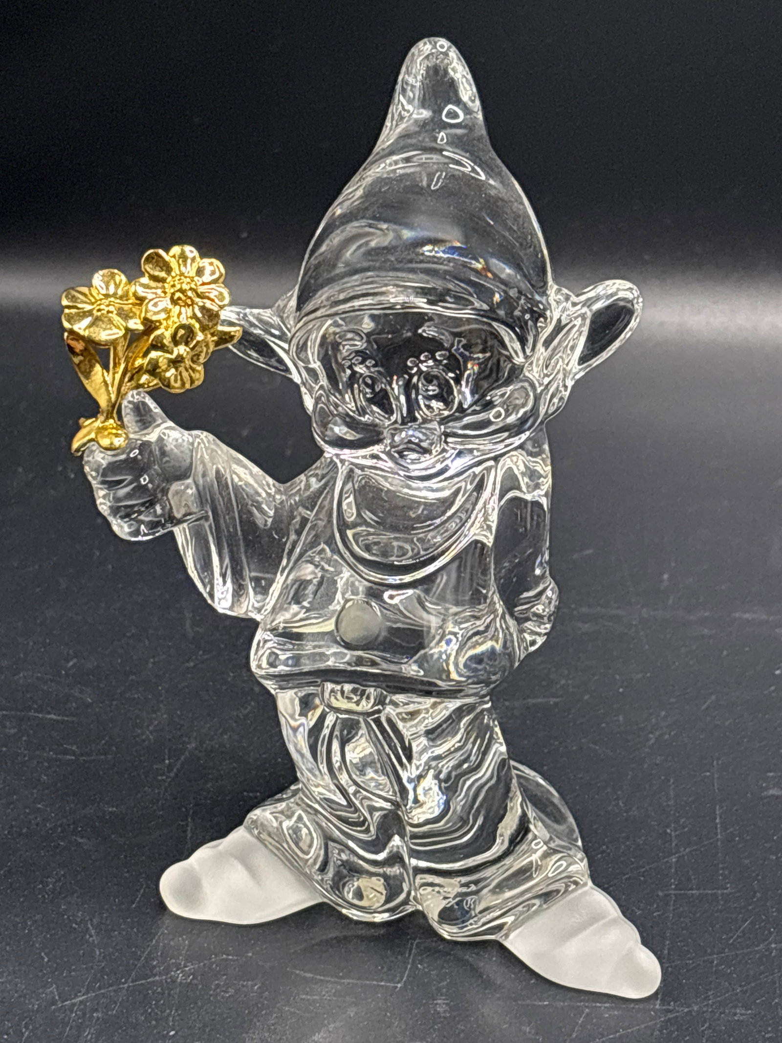 Disney Lenox Classics crystal 5.25 inch figurine of Dopey from Snow White: Disney Lenox Classics crystal figurine of Dopey from Snow White and the Seven Dwarfs holding daisies accented in 24k gold.Brand: Lenox, part of the Disney Crystal Collection.Material: Lead crystal
