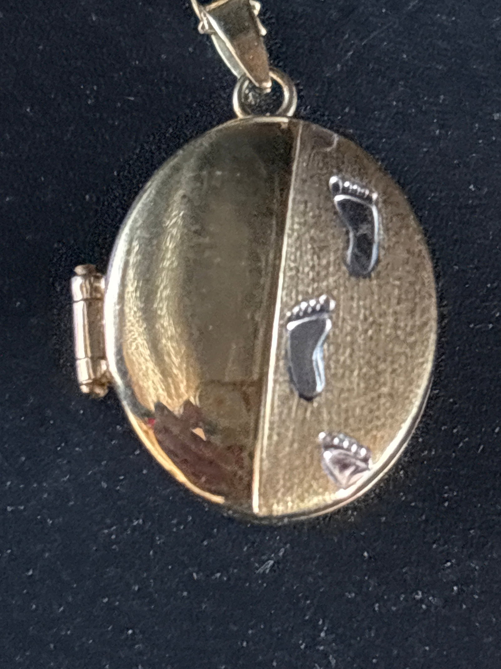 1.85 grams 9ct yellow gold oval locket necklace featuring an engraved "Footprints in the Sand": 9ct yellow gold oval locket necklace featuring an engraved "Footprints in the Sand" motif, usually accented with rhodium or white gold plating for contrast.Design DetailsThe Motif: This timeless piece