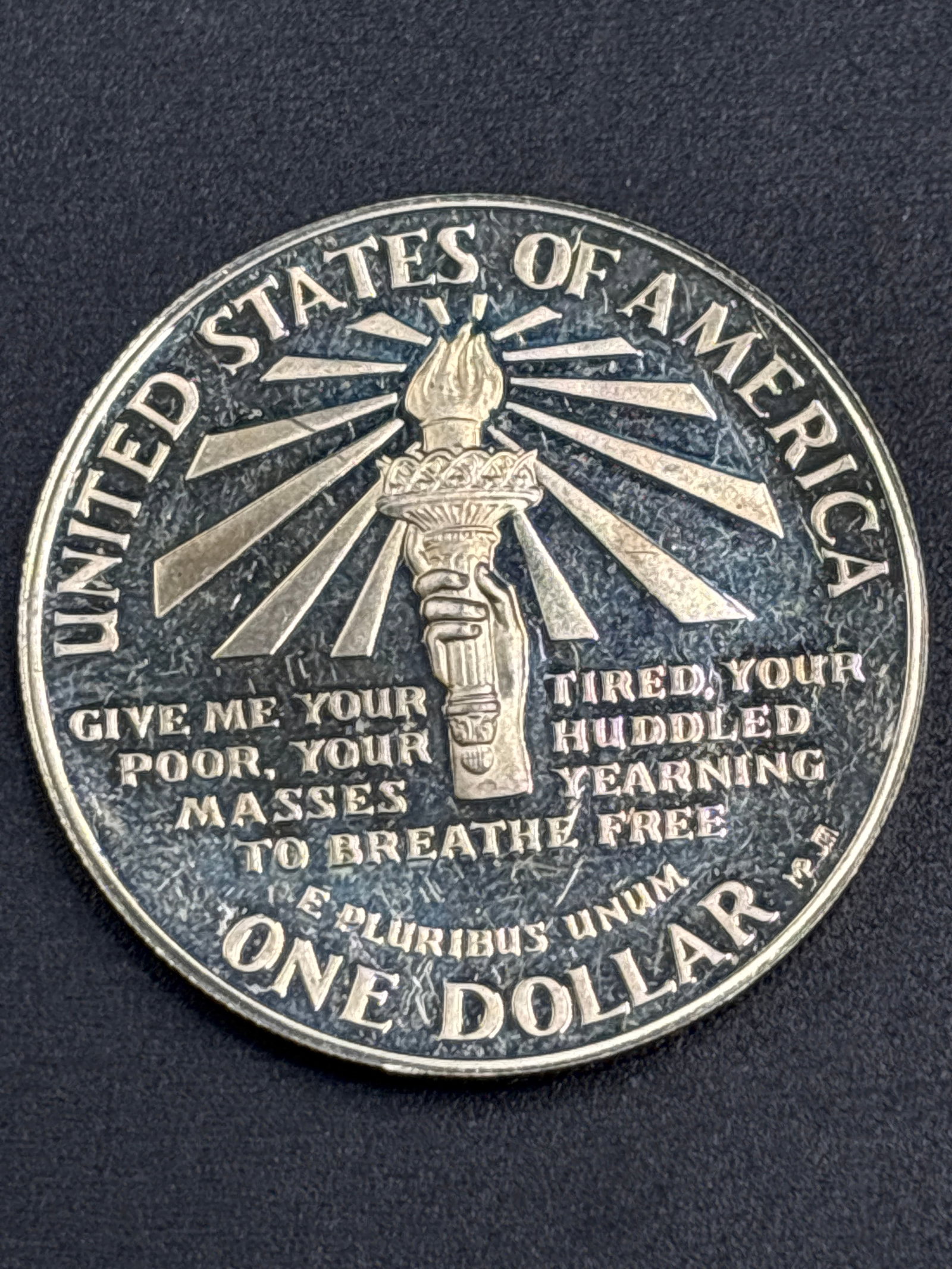 26.73 grams 99% Silver 1986-S Statue of Liberty Commemorative Silver Dollar: 1986-S Statue of Liberty Commemorative Silver Dollar featuring the Statue of Liberty and the Ellis Island Immigration Building on the obverse. It is composed of 90% silver and 10% copper, containing 0