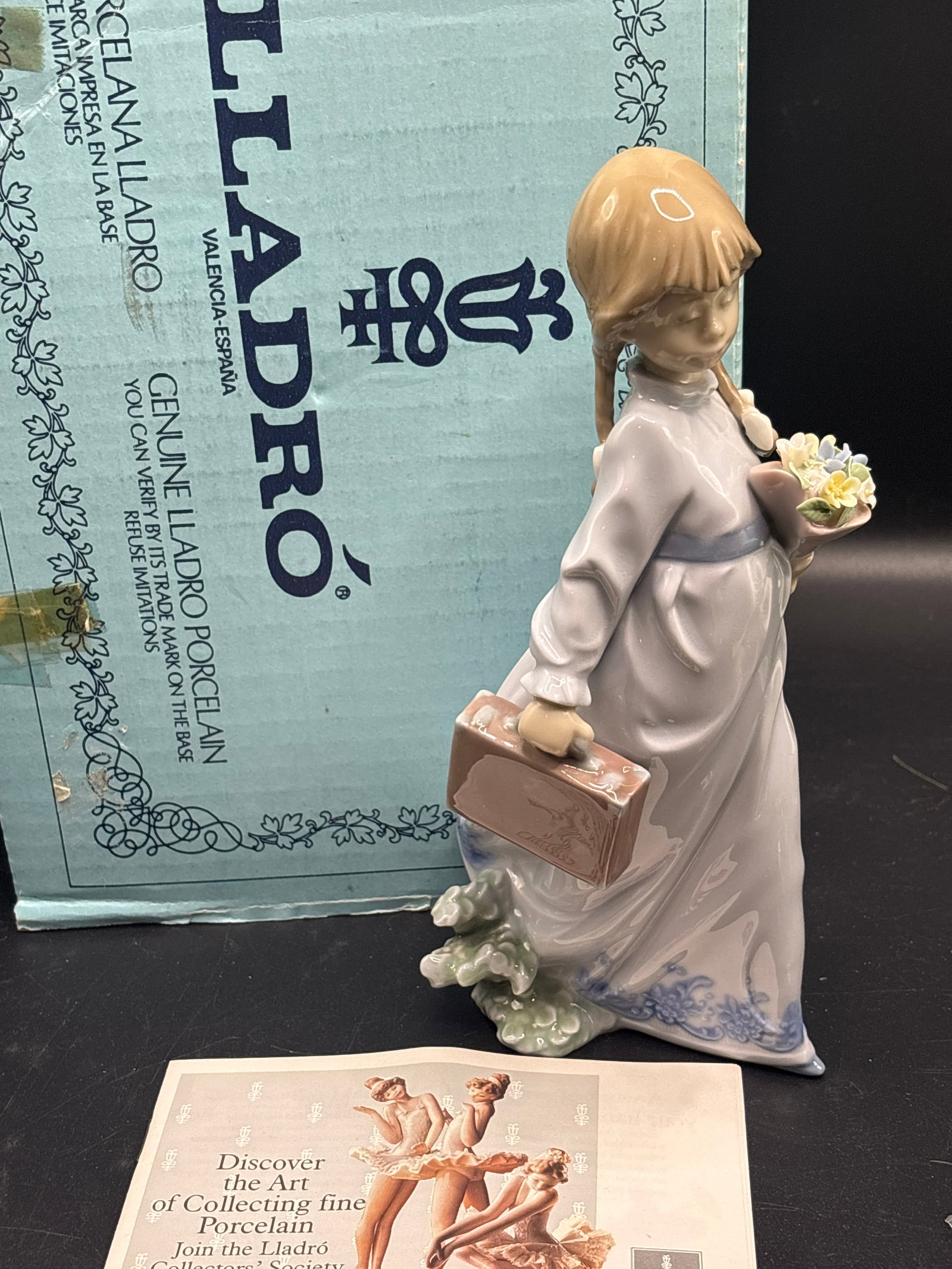 Lladró porcelain 8.25 inch figurine "School Days" (Flores a la Maestra) Figurine #7604: With box, Lladró "School Days" (Flores a la Maestra) Figurine #7604, a glossy porcelain piece featuring a young girl holding a bouquet of flowers and a school case.Designer: Antonio RamosRelease Year