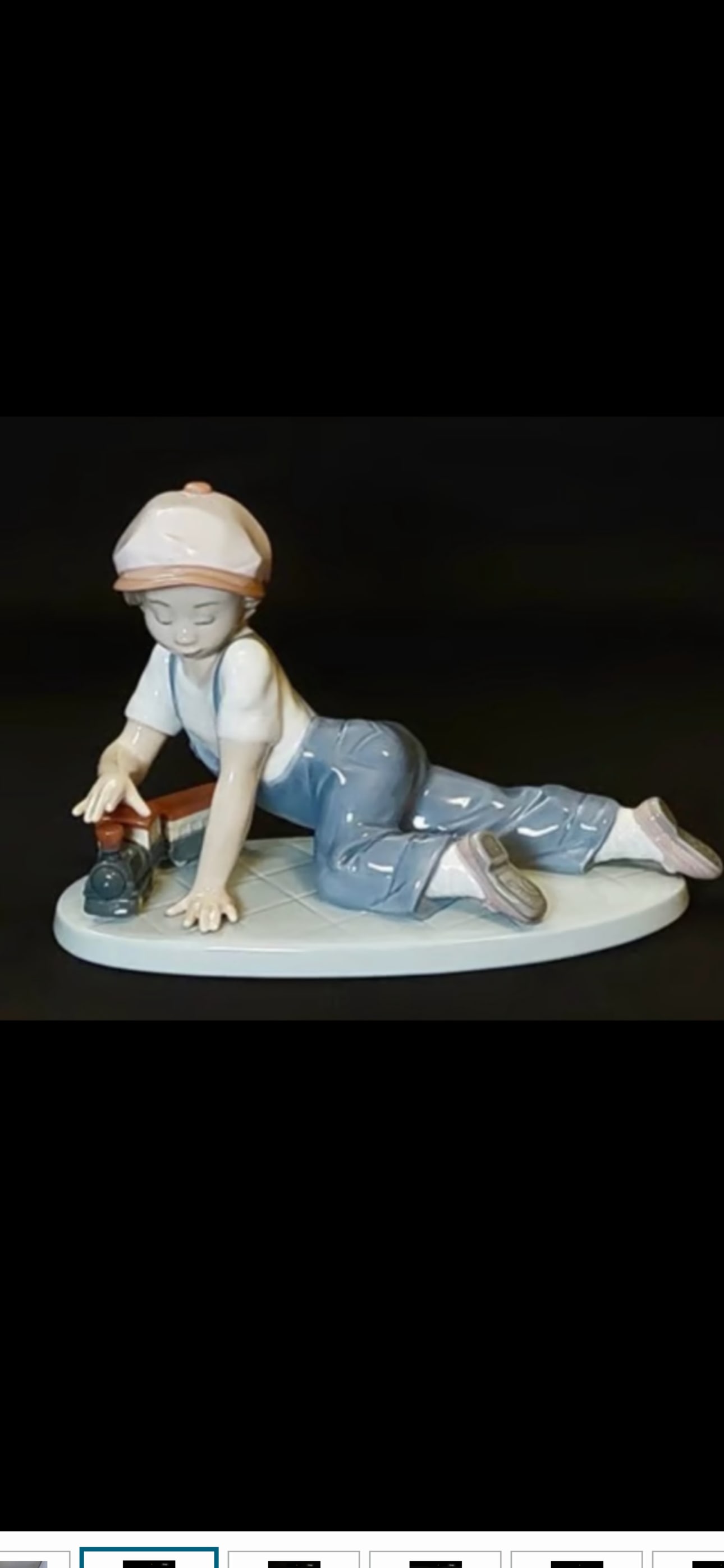 vintage Lladró "All Aboard" Figurine #7619: With box, Lladró "All Aboard" Figurine #7619 is a hand-painted glazed porcelain piece depicting a young boy in blue overalls and a cap crawling next to a toy train. Sculpted by Antonia Belles, it was