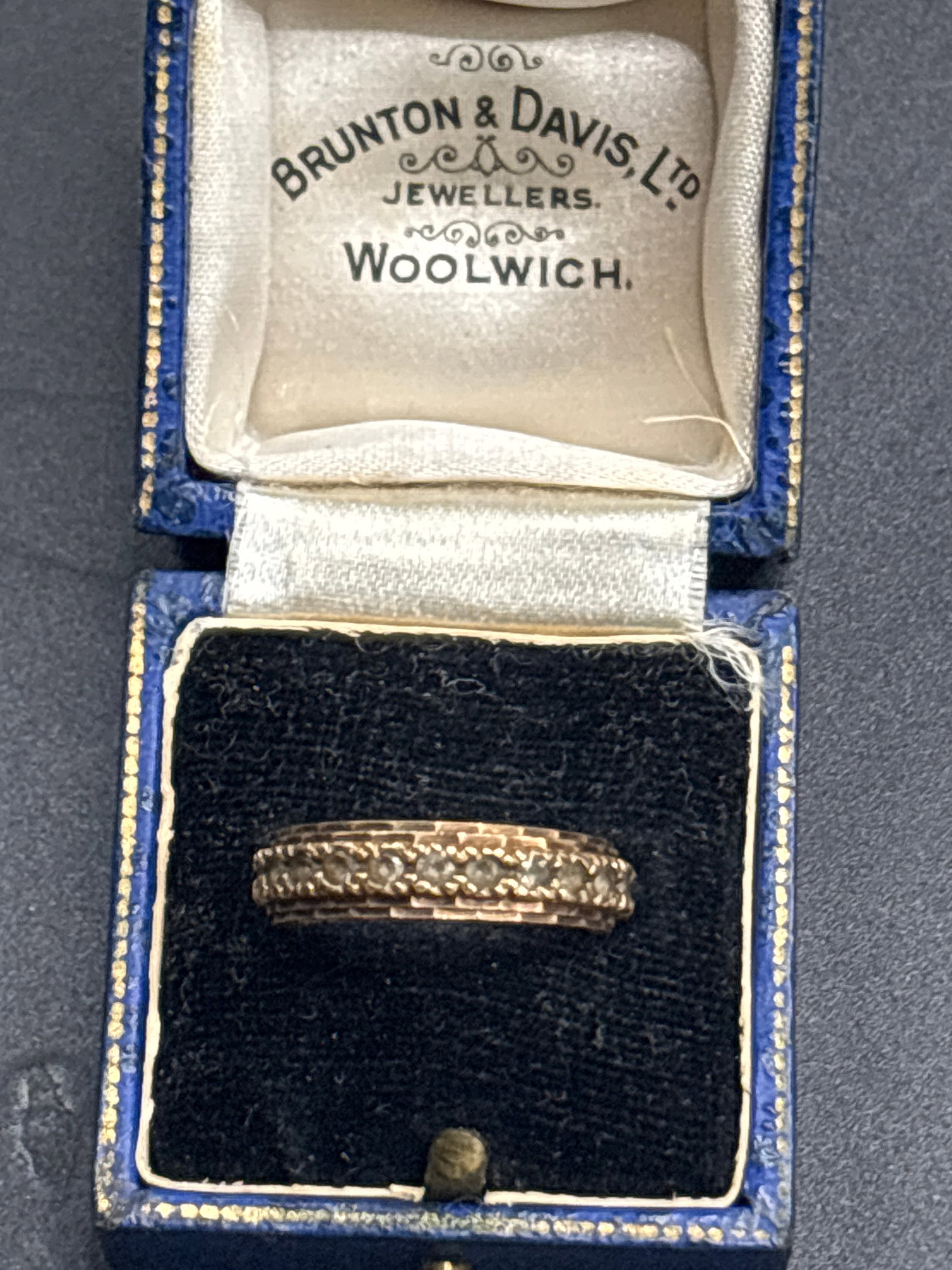 3 grams 9 k yellow gold eternity-style band ring: A 9ct gold eternity ring, stamped 9ct, size 5.75-6; 3 grams gross... antique eternity-style band ring resting inside a blue velvet-lined presentation box. The ring features a central row of flush-set 