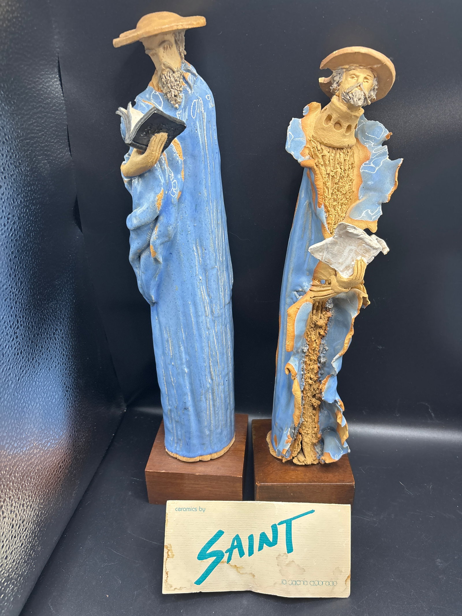 Two works of Gerald "Gerry" Saint Germain tall slender statues: Two works of Gerald "Gerry" Saint Germain statues , rustic, elongated, and highly textured figures wrapped in vibrant glazed robes—often in shades of cerulean blue.He was a highly regarded twentieth