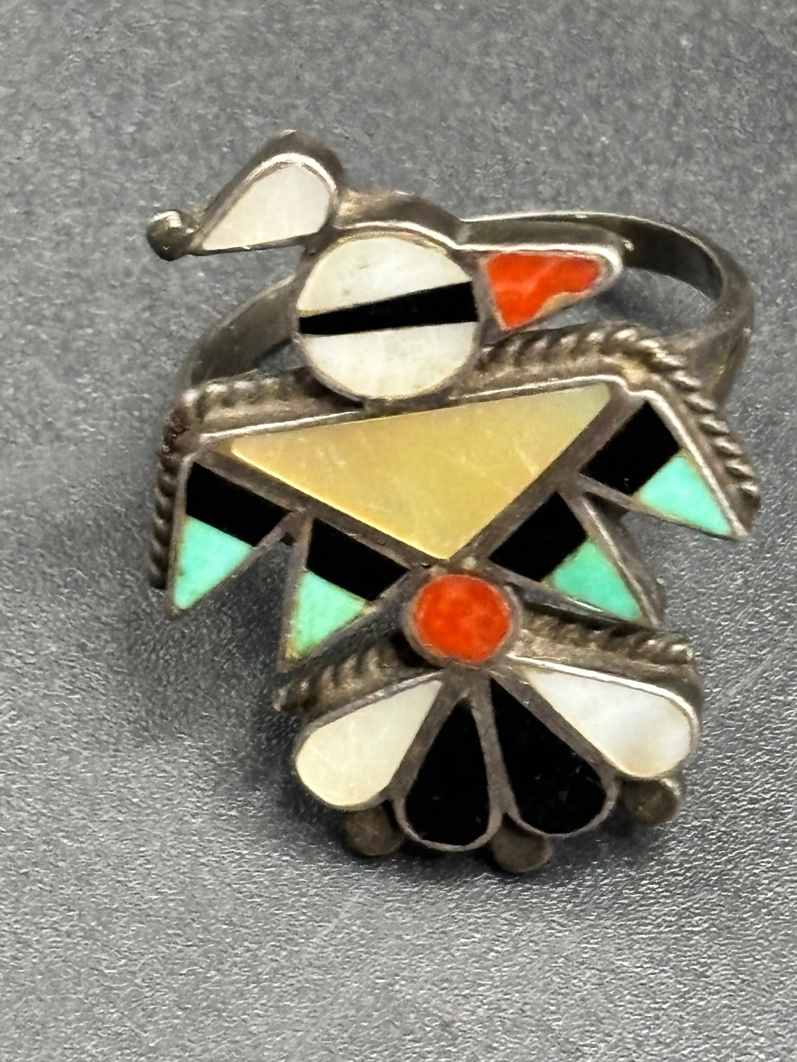 early sterling vintage Zuni Native American stone inlay ring: early vintage Zuni Native American stone inlay ring. It features intricate stone-to-stone or channel inlay work forming a stylized Thunderbird or Knifewing deity figure, which is highly characteristic
