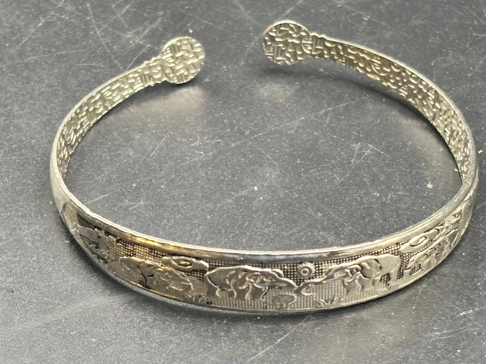 14.4 grams vintage sterling silver elephant cuff bracelet: 14.44sterling silver elephant cuff bracelet featuring a parade of relief-carved elephants marching across the band with decorative floral or scrollwork accents. It is typically designed in an open, ad
