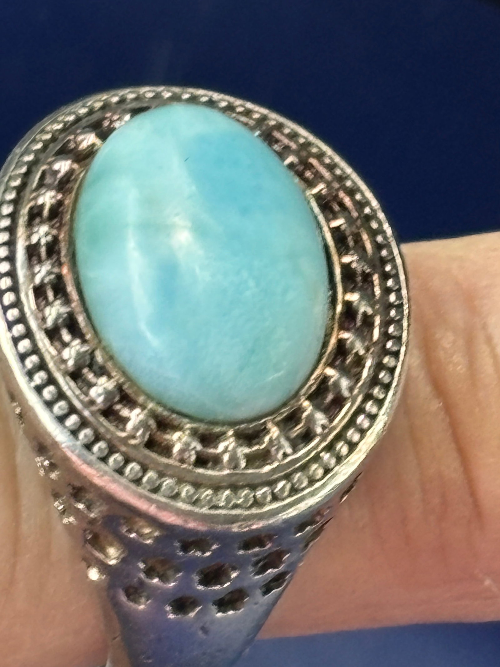 sterling silver statement ring featuring a light-blue oval stone: statement ring featuring a light-blue oval stone—resembling natural larimar or turquoise—set in an ornate silver-toned metal band with a textured, beaded halo frame.FeatureDetailsTypeStatement / F