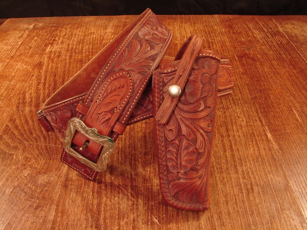 El Paso Saddlery made Colt holster: El Paso Saddelry made Colt holster. Texas made tooled gun rig with fine engraved buckle. Has 11 .45 Colt rounds. A very nice rig. Will fit from 32 -36 waist.