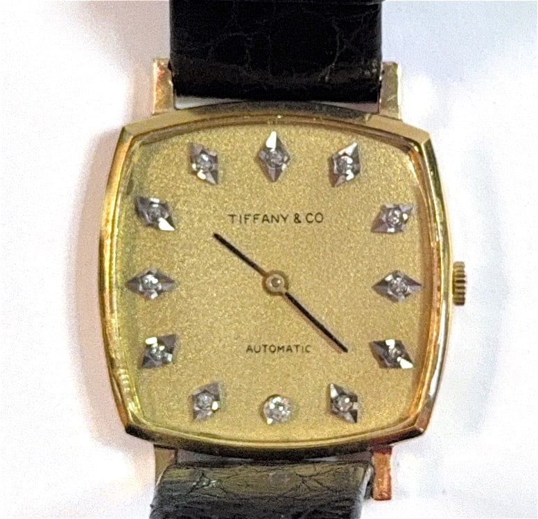 Vintage 14K Tiffany & Co. Automatic Men's Dress Wristwatch: 14K WATCH. Watch from the mid-20th century (circa 1960s). It features a distinctive yellow gold cushion-shaped case housing a textured gold-tone dial. The hour markers are designated by 12 inset diamo