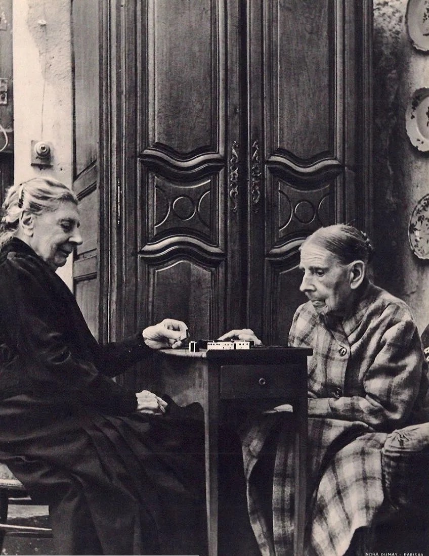 Nora Dumas (Hungarian, 1890-1979) Print: Nora Dumas (Hungarian, 1890-1979) Print. Deux Centenaires Jouant aux Dominos. Printed in 1939. 9.00 x 11.00 inches Not hand-signed unless otherwise stated. Photomechanical Print. Lots that contain