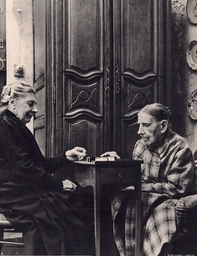 Nora Dumas (Hungarian, 1890-1979) Print: Nora Dumas (Hungarian, 1890-1979) Print. Deux Centenaires Jouant aux Dominos. Printed in 1939. 9.00 x 11.00 inches. Not hand-signed unless otherwise stated. Photomechanical Print. Lots that contain nu