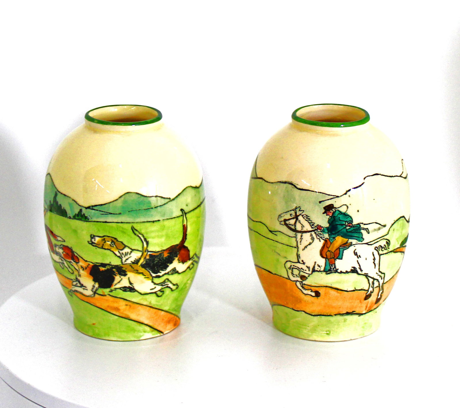 Pair of Haag Austria Pottery Vases of Hunting Scene.: Pair of Austrian Haag Pottery 4 1/2" tall cabinet vases of a hunting scene that spans between the two vases. One with the hunter on horseback and the other with the three hounds hot on the trail. Who 