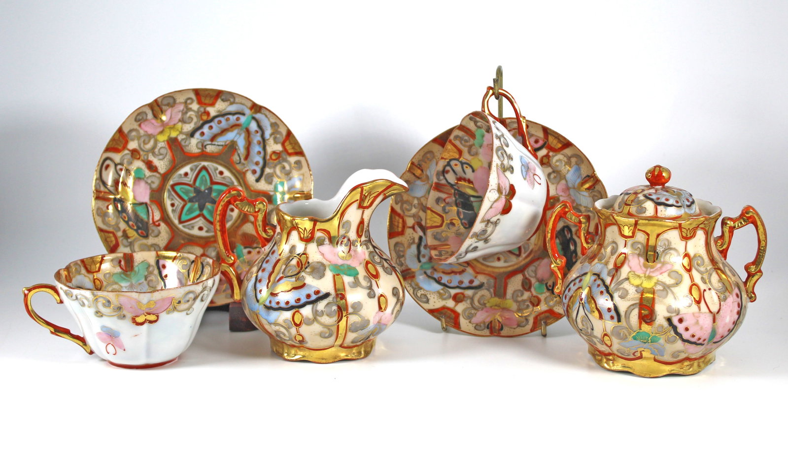 Antique Japanese Kutani Porcelain Service Butterflies: Antique Japanese Kutani Porcelain Service from the Meiji period (1868-1912). Beautiful overglaze enamels, hand-painted with butterflies and foliate. Set includes lidded sugar, cream and two cups with 