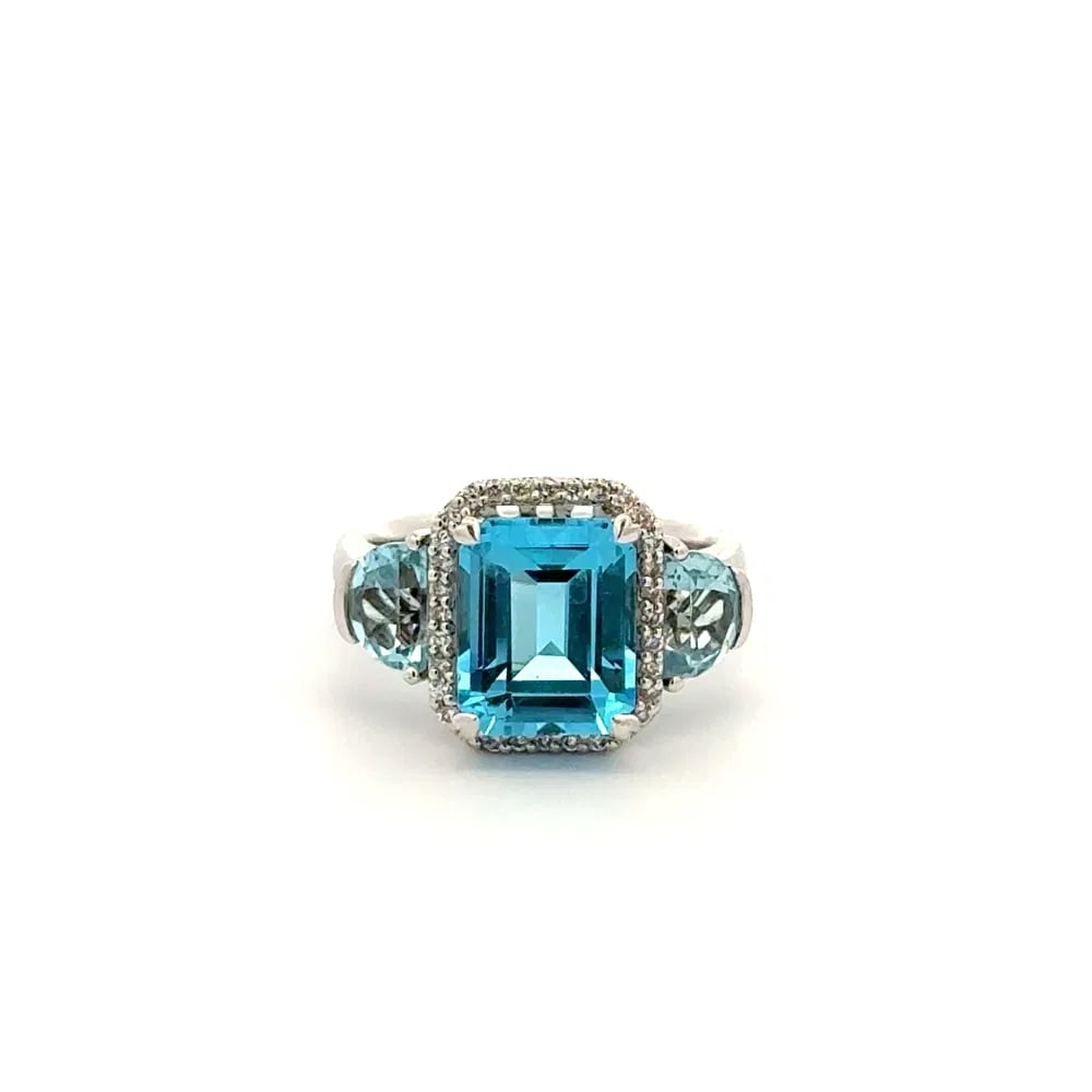 14k WG Blue Topaz Diamond Ring: Contemporary 14k white gold ring featuring a 3ct emerald cut blue topaz, additional 0.70tcw topaz accents, and 0.16tcw diamonds. A bold, sparkling design with luxury weight. - Center: Emerald cut blue