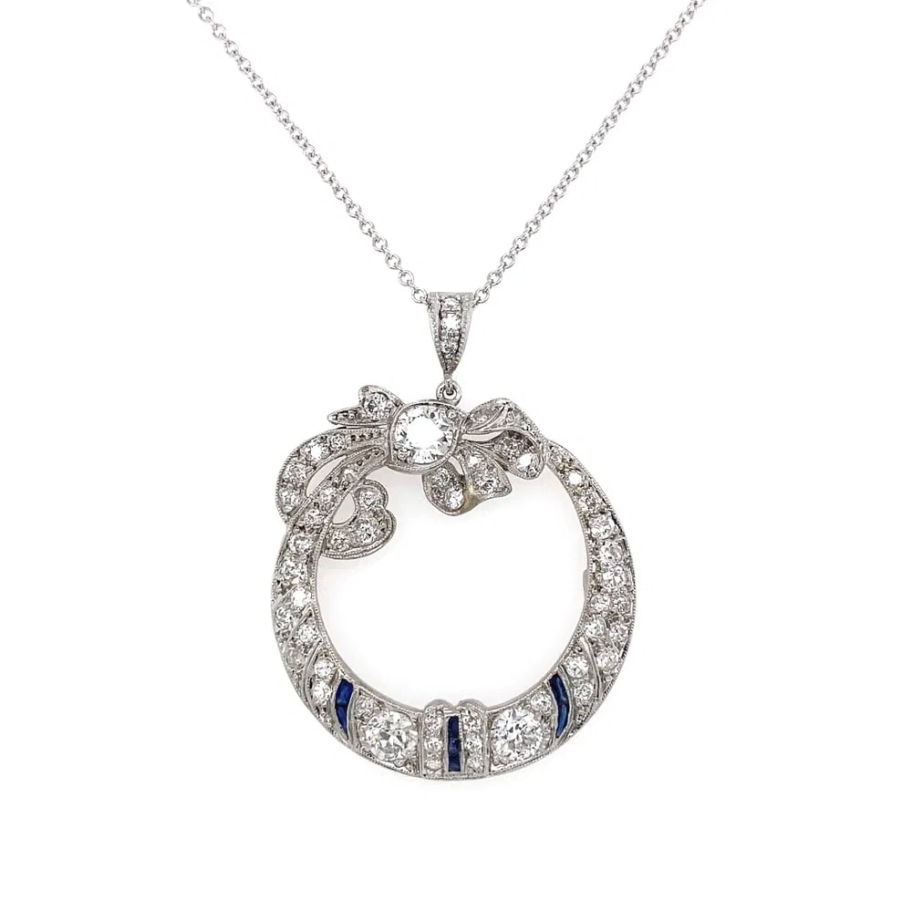 Art Deco Platinum 2.25tcw Diamond Sapphire Pendant: Art Deco open circle bow-shaped pendant in platinum with approx. 2.25tcw old European and old cut diamonds plus synthetic sapphires, on 14k white gold 16" chain. - Center diamonds: 3 Old European cuts