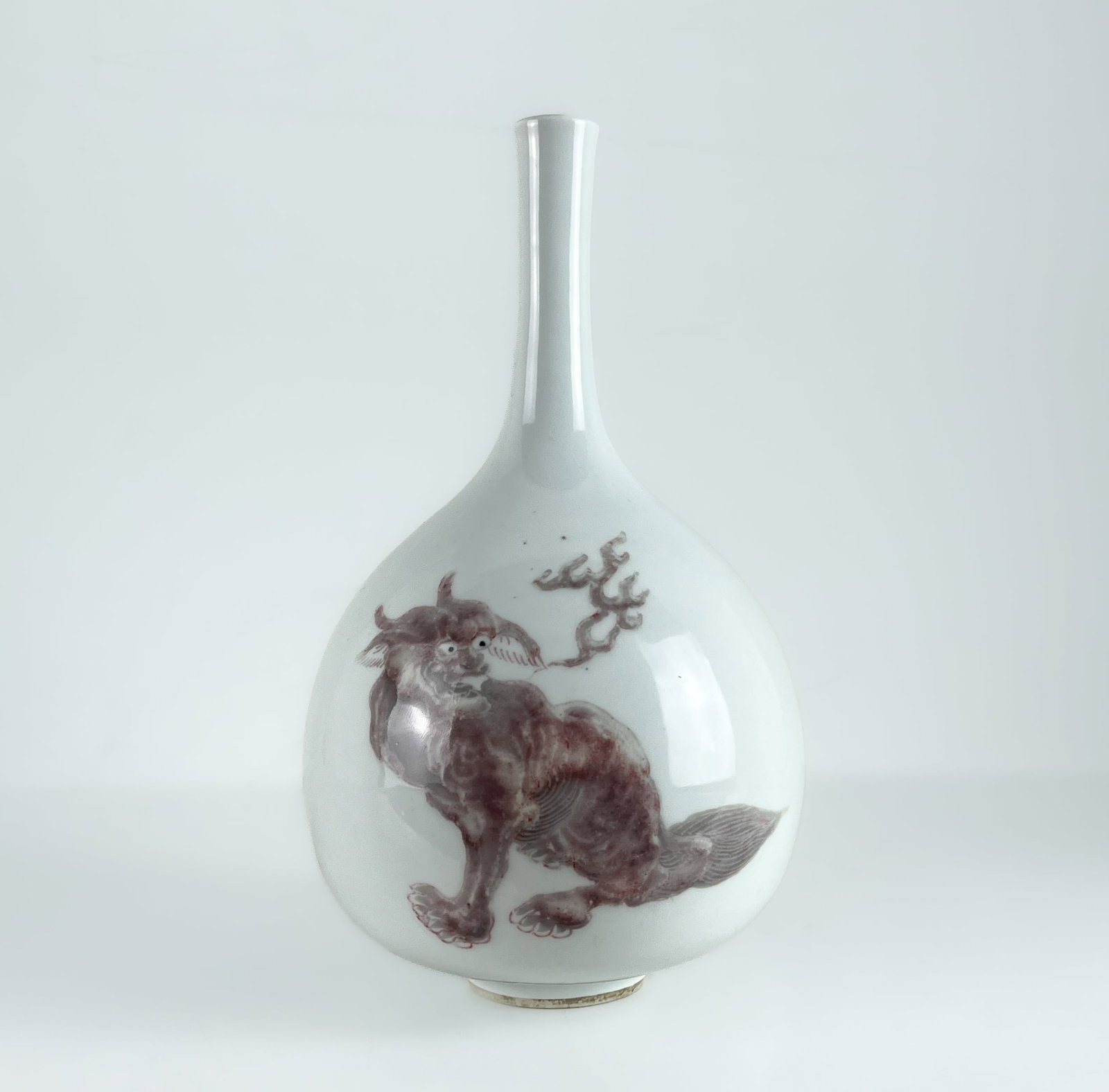 A CHINESE UNDERGLAZE COPPER-RED BOTTLE VASE, KANGXI PERIOD: A CHINESE UNDERGLAZE COPPER-RED BOTTLE VASE DECORATED WITH THREE LIONS, KANGXI PERIOD 22 CM H. 4.5 CM BASE DIAMETER 13 CM MAX WIDTH GOOD CONDITION