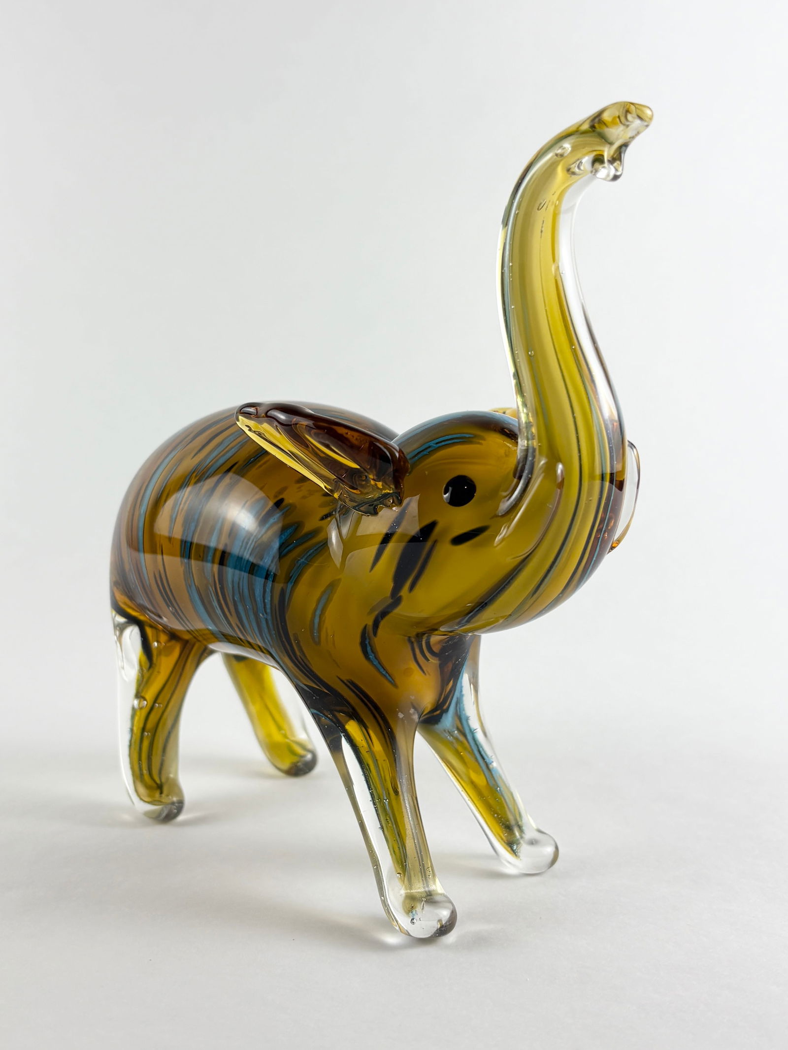Murano-style Art Glass Elephant: Art Glass Elephant, Glass Elephant Glass Height: 8 inches A decorative art glass elephant in the style of Murano, featuring multicolored striping. One glass elephant is included.