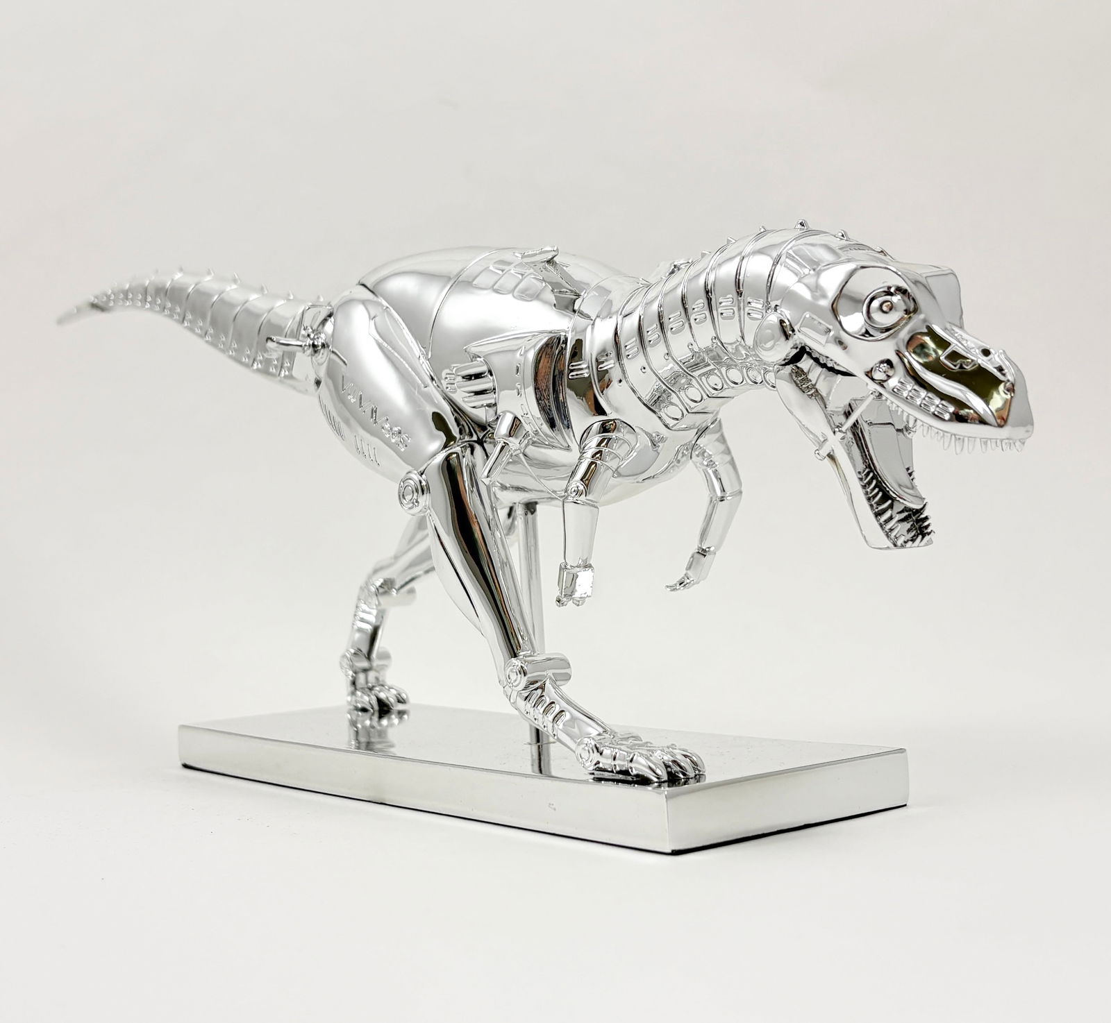 Sorayama – Tyrannosaurus Figure (In Box): Sorayama, Tyrannosaurus Figure 8 x 17 x 4 inches A Tyrannosaurus figure by Sorayama, presented on a display base. The figure is shown with its original box included.