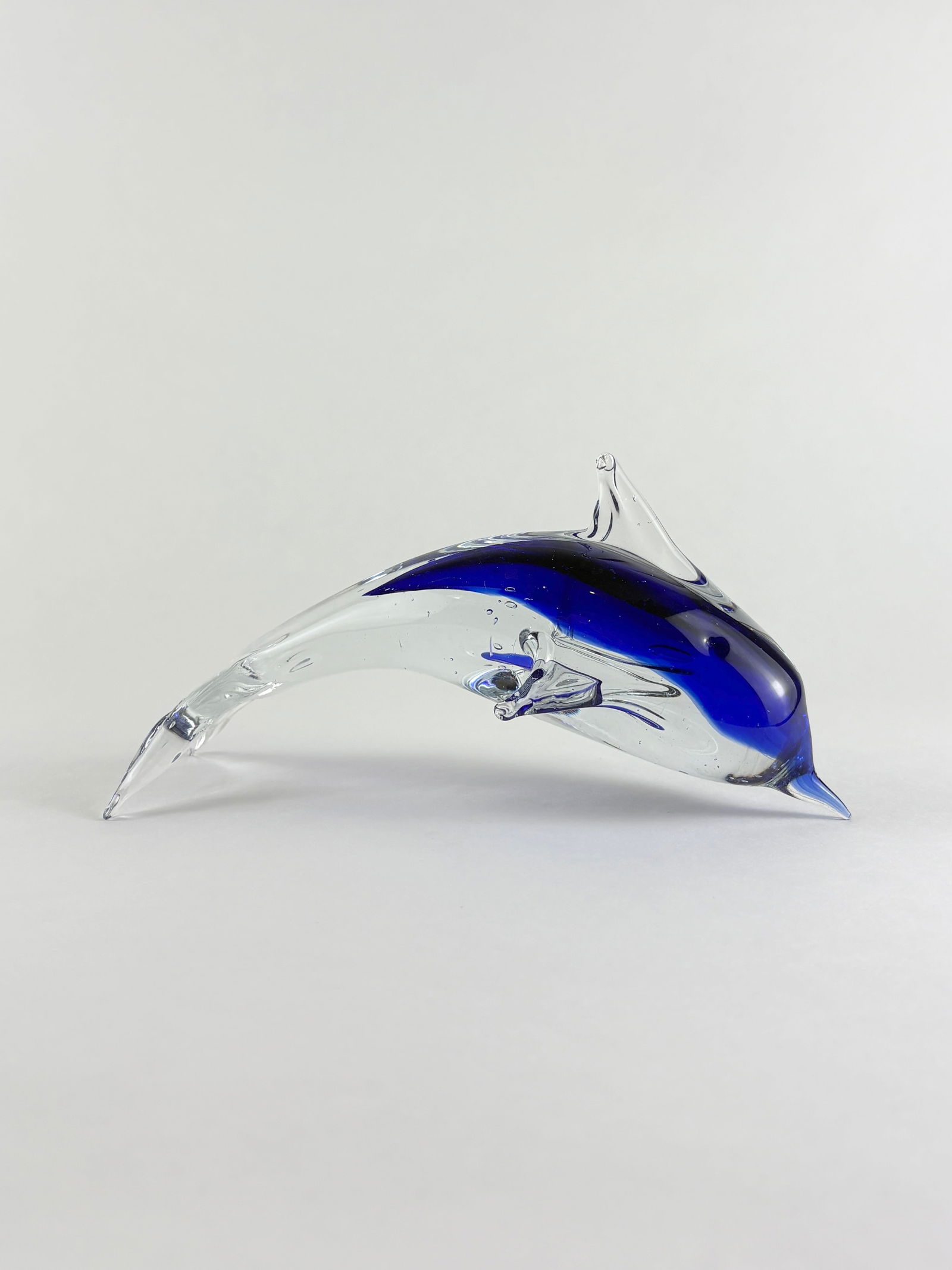 Art Glass Dolphin: Art Glass Dolphin, Glass Dolphin Glass Height: 7 inches A decorative art glass dolphin with clear fins and a blue-toned body.