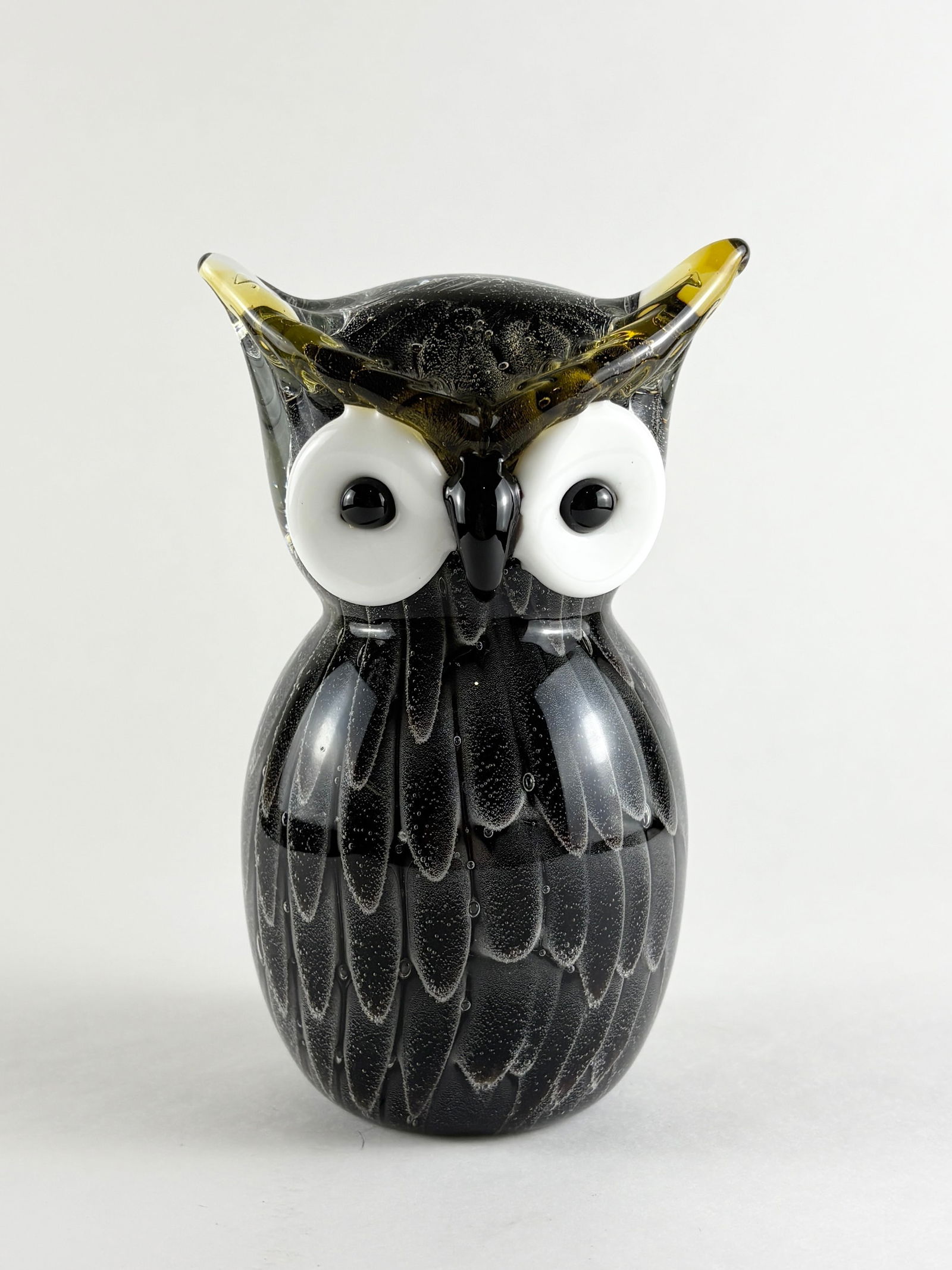 Glass Owl Sculpture: Decorative hand-blown glass owl sculpture with a rounded form, applied white glass eyes, and stylized feather detailing. The figure features a predominantly black body with subtle internal texturing