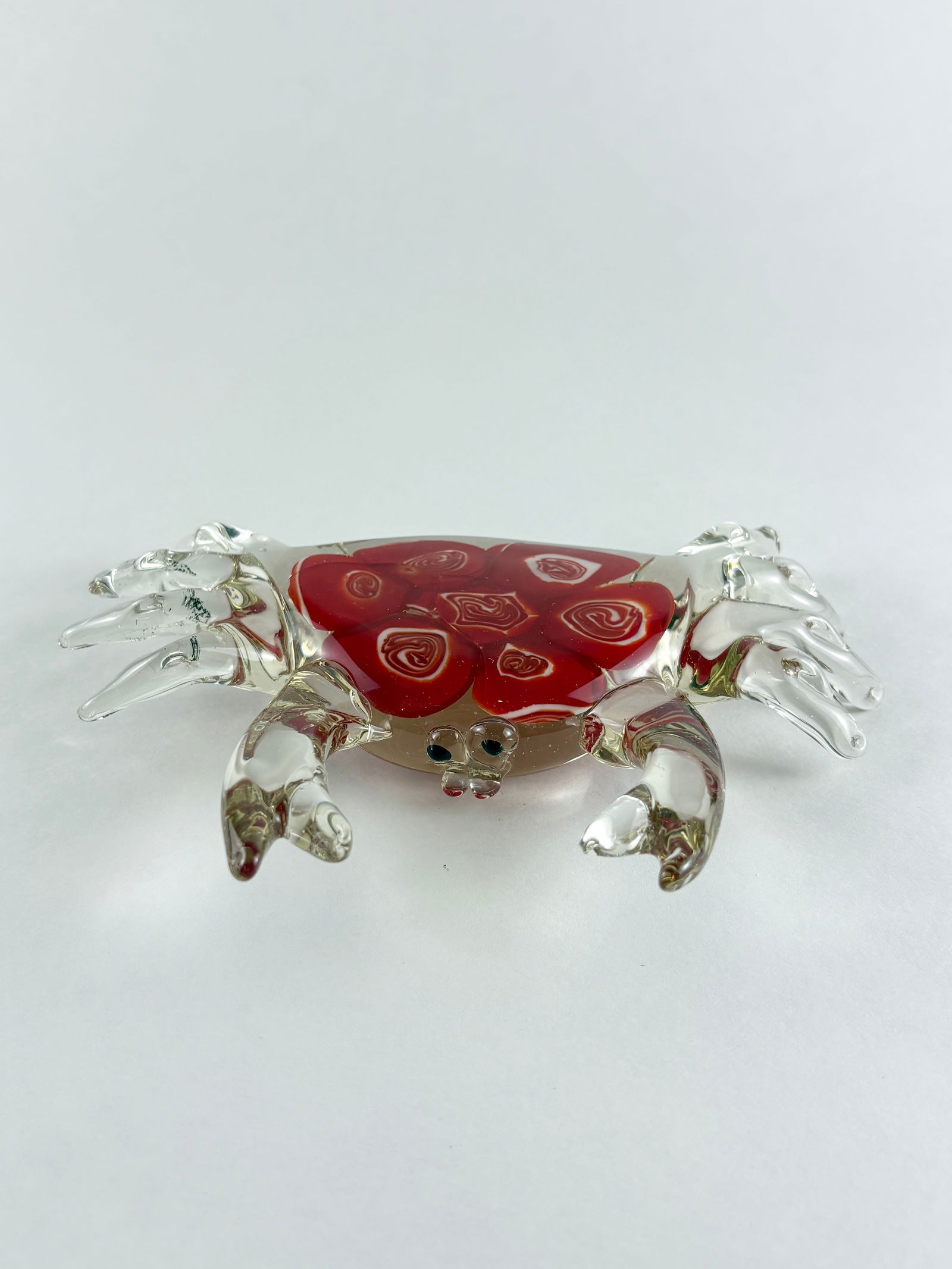 Glass Crab Sculpture: Decorative hand-blown glass crab sculpture featuring a vivid red body with applied spiral detailing and clear articulated legs and claws. The form is stylized yet naturalistic, with applied eyes and