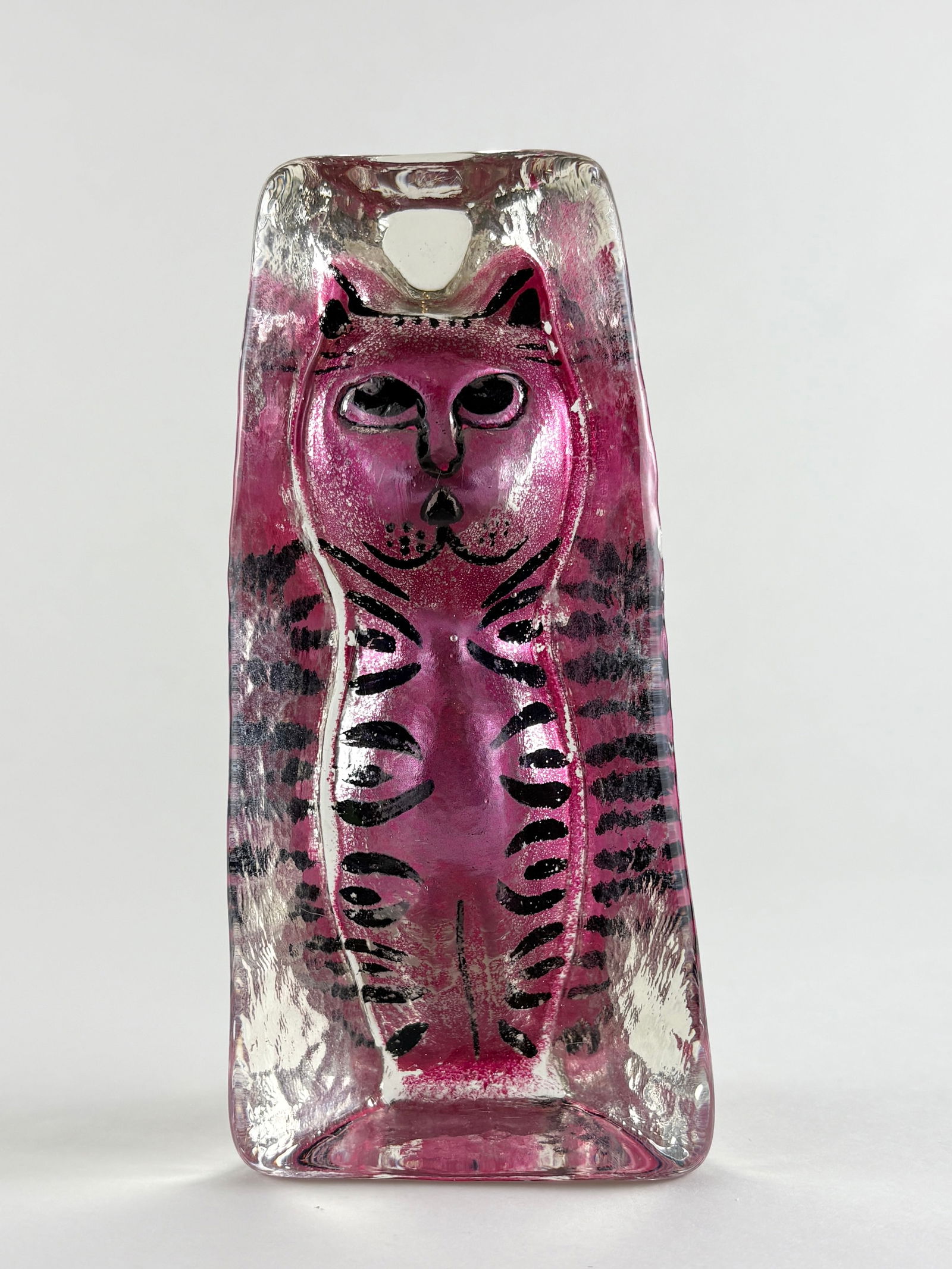 Glass Cat Sculpture: Stylized hand-blown glass cat sculpture rendered in a vibrant magenta-pink tone with black linear detailing defining the facial features and body markings. The figure is vertically oriented with a