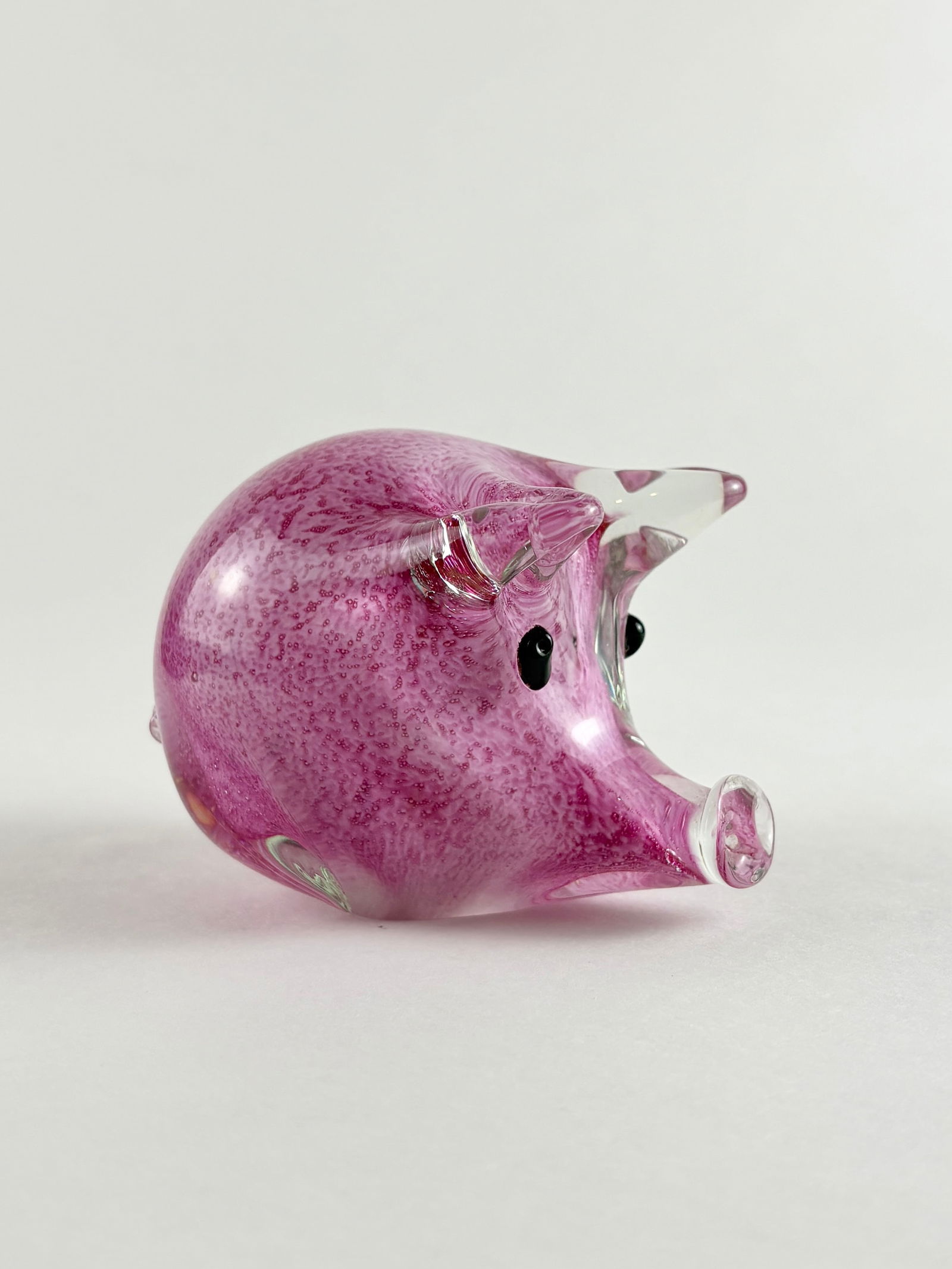 Glass Pig Sculpture: Clear and pink art glass pig sculpture featuring a rounded body with applied facial details. The piece is formed in a solid, hand-shaped style with mottled pink coloration throughout, giving it a