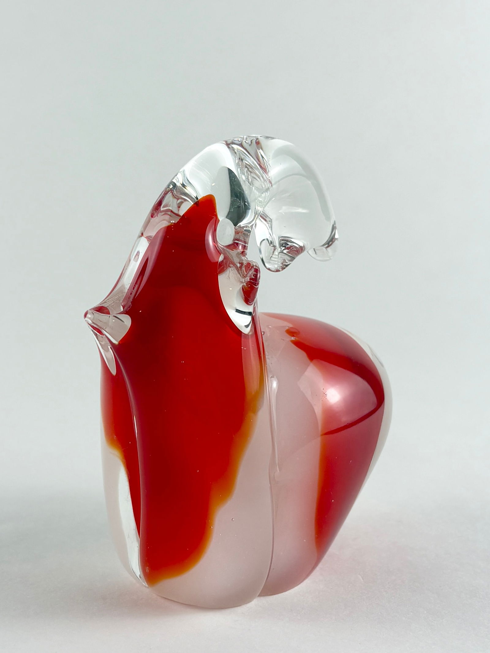 Glass Elephant Sculpture: Decorative hand-blown glass elephant sculpture featuring a stylized form with a clear head and layered red, orange, and translucent tones throughout the body. Executed in a smooth, free-form