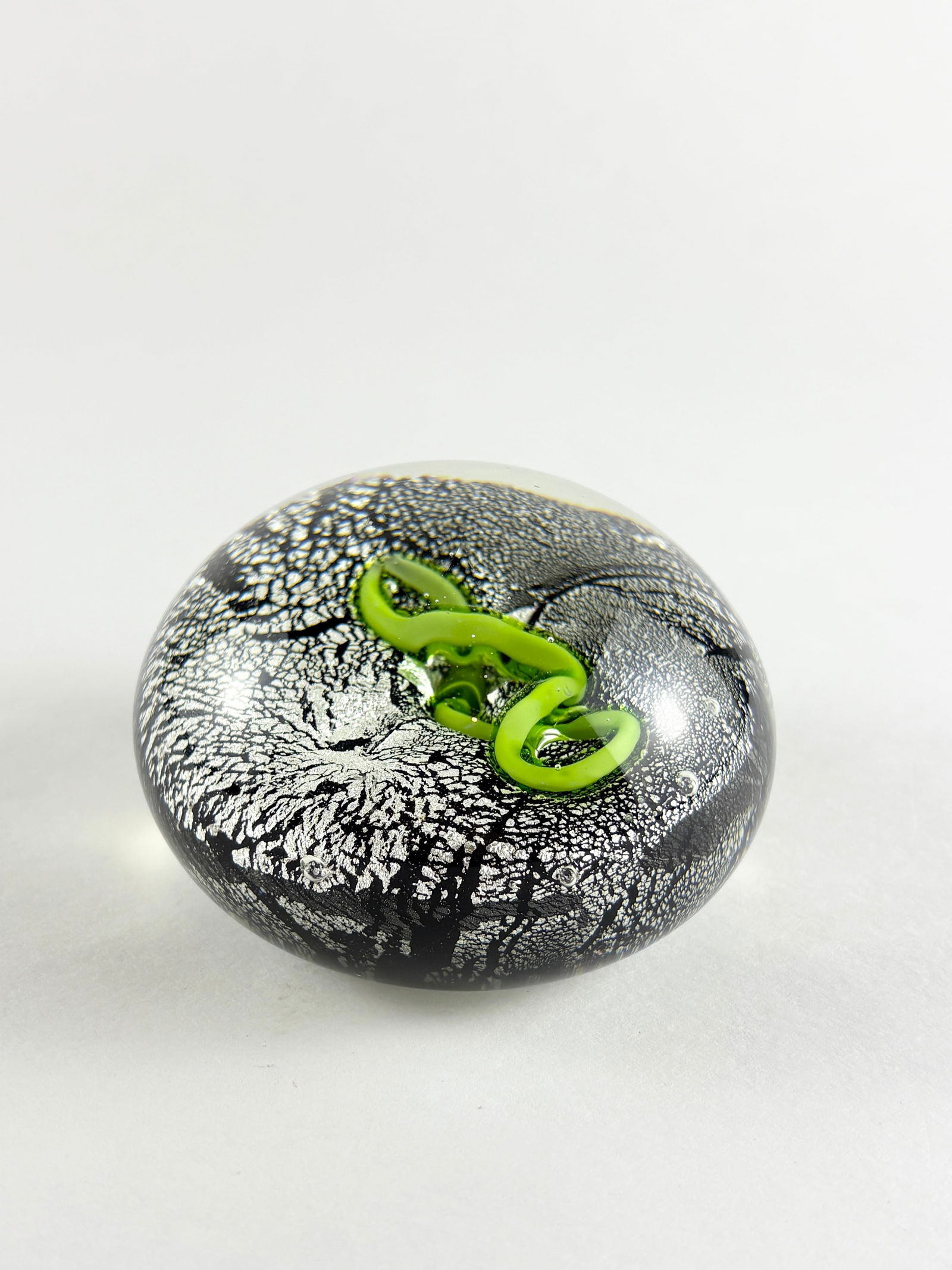 Murano Style Glass Ball Sculpture: Murano style hand-blown glass ball sculpture featuring a black and silver speckled ground with an applied green coiled serpent motif embedded beneath the surface. The piece demonstrates layered glassw