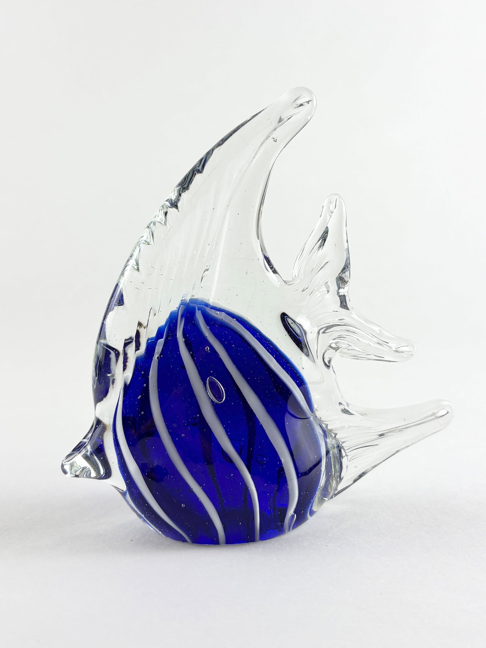 Glass Fish Sculpture: Decorative art glass fish sculpture featuring a deep cobalt blue body encased in clear glass, accented with applied white trailing lines and extended clear fins. The form is stylized with pronounced d