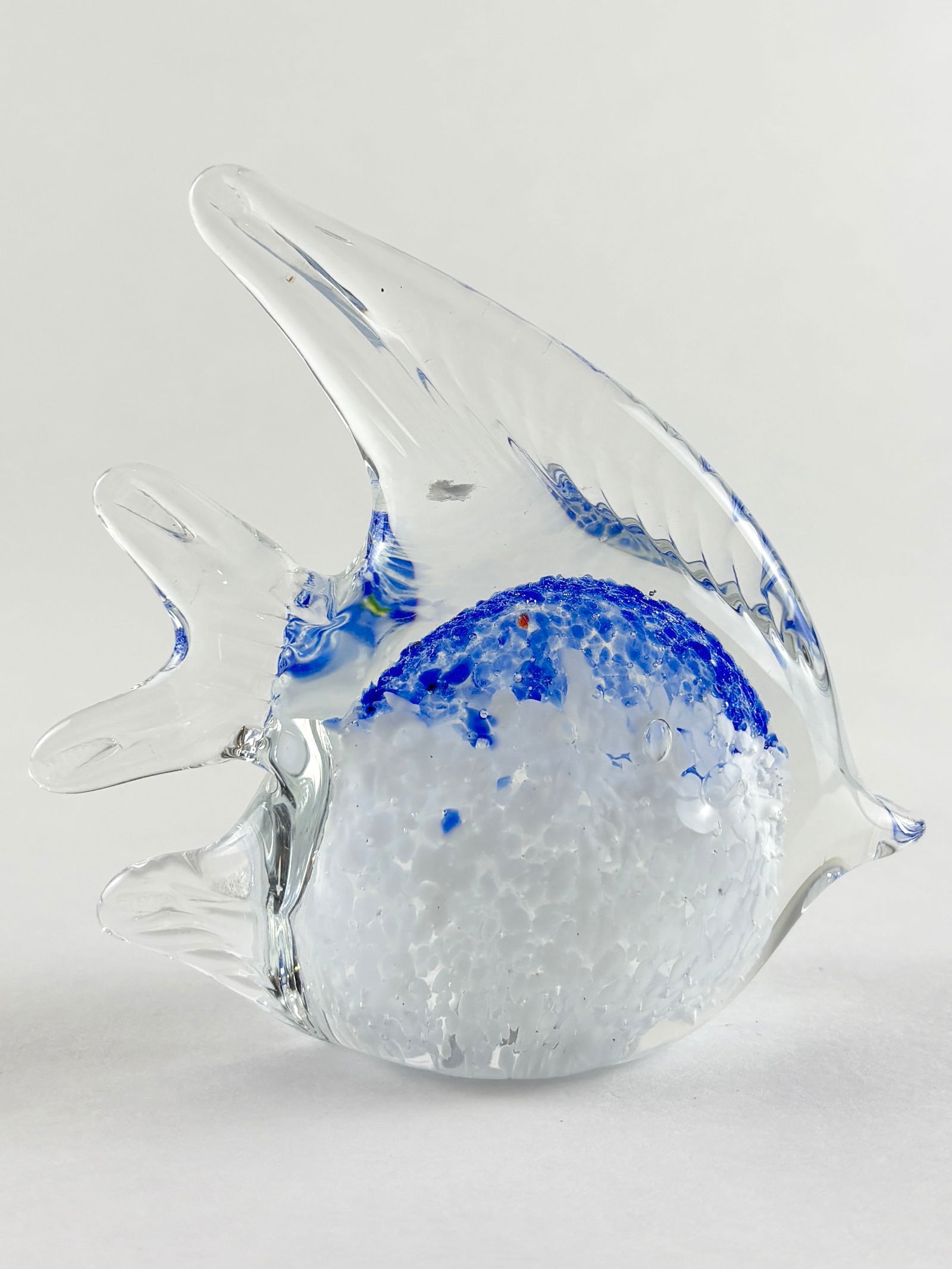 Glass Fish Sculpture (Murano Style): Decorative art glass fish sculpture executed in clear glass with cobalt blue inclusions and controlled bubbles forming a rounded central body with extended fins and tail. The use of color spotting, in