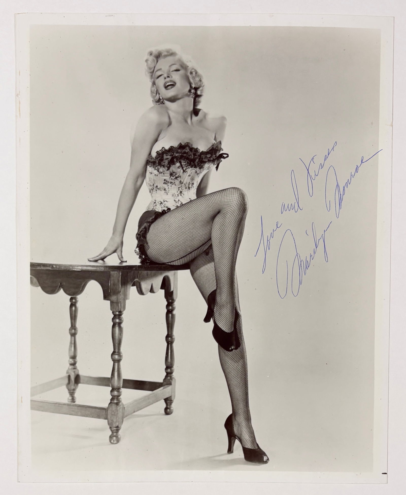 Marilyn Monroe – Seated Portrait Photograph, Hand Signed: Marilyn Monroe (1926–1962) Seated Portrait photographic print on paper, ink inscription 7.75 x 10 inches This photographic portrait depicts Marilyn Monroe seated on a small table, posed in a