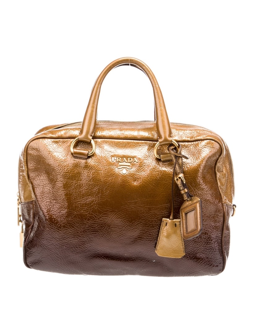 Prada Bauletto Brown Vernice Leather Top Hdl Bag: Condition is: very good, pre-owned. Details: brown vernice leather, printed, gold-tone hardware, rolled handles, logo jacquard lining & dual interior pockets, zip closure at top, protective feet at ba