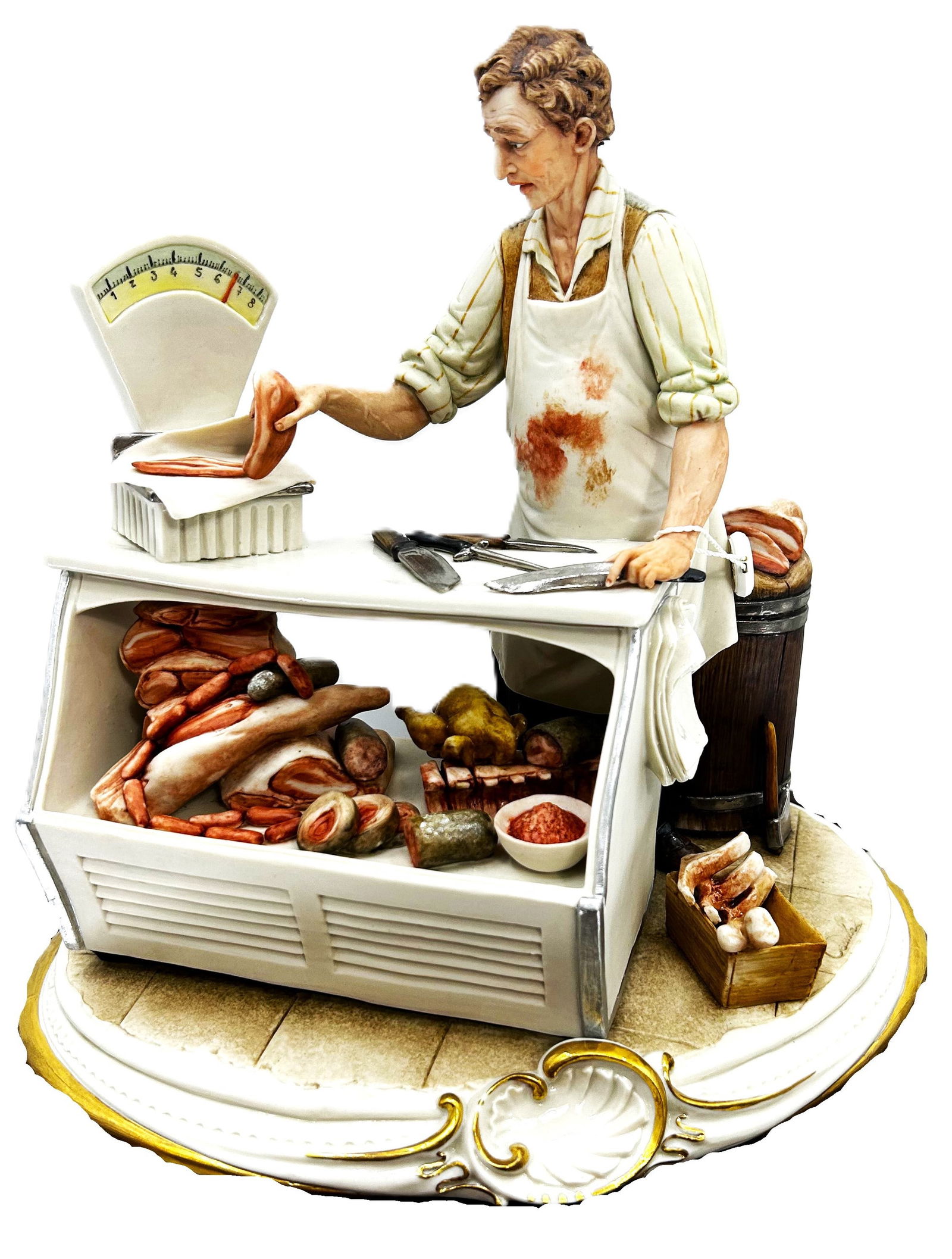 Capodimonte Porcelain Figurine: The Butcher: This detailed Capodimonte porcelain figurine depicts a butcher at work behind his display counter. The butcher, wearing an apron, is weighing a piece of meat on a scale. The display case is filled wit