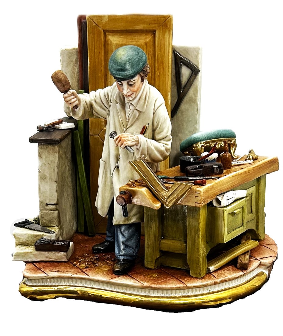 Capodimonte Porcelain Figurine: Artisan at Work: This detailed Capodimonte porcelain figurine depicts an artisan meticulously working at a workbench. The figure, wearing a cap and a work coat, is using a tool and mallet, surrounded by various tools