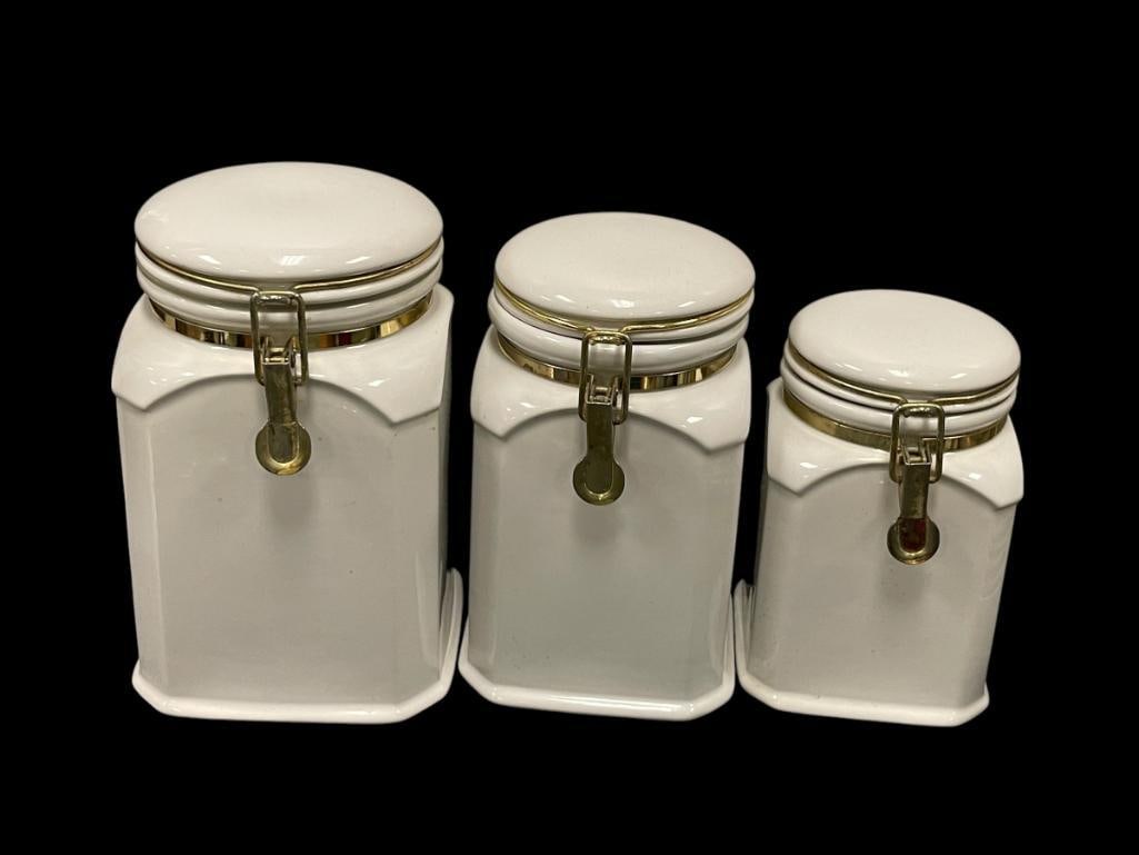 SET OF THREE KITCHEN CERAMIC CANISTERS IN GRADUATING SIZES WITH HINGED LIDS: SQUARE BODIES WITH ROUNDÂ LIDS 7 1/2", 8 1/2", AND 9 1/2" H