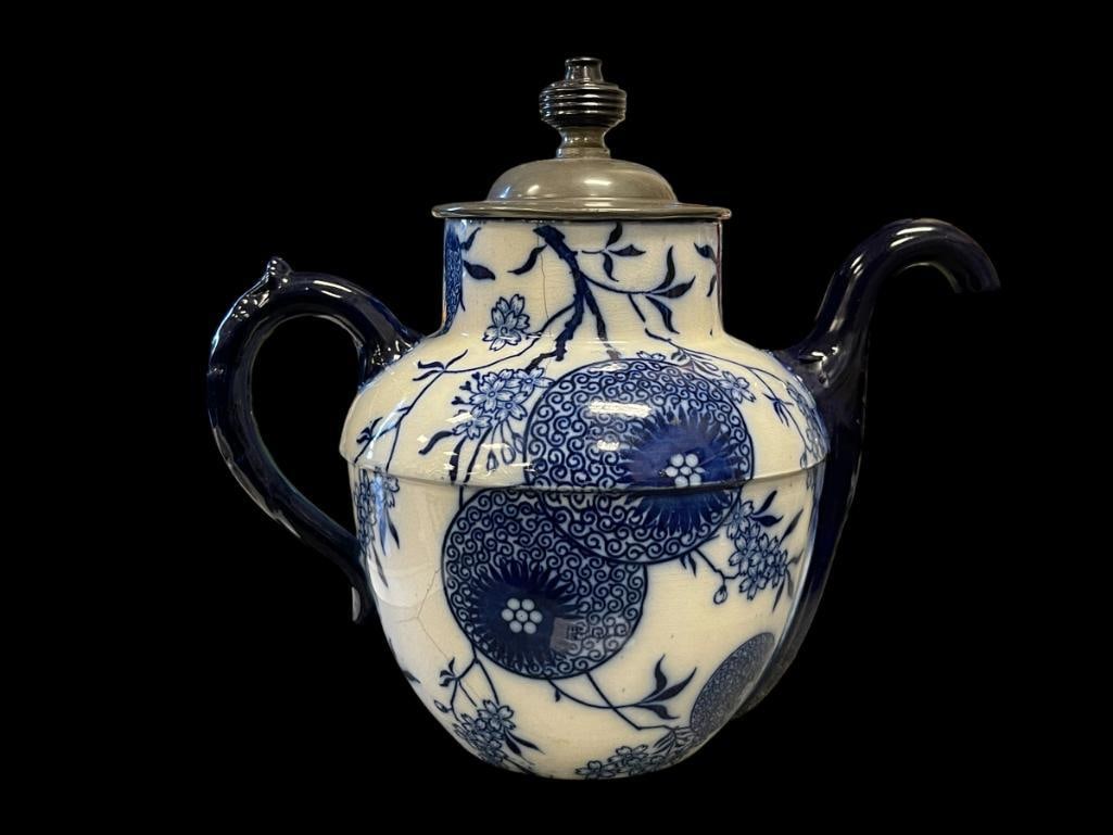 ANTIQUE 1886 FLO-BLUE TEAPOT DOULTON'S BURSLEM FOR JJ ROYLE MANCHESTER NO. 6327: BLUE ANDF WHITE FLORAL AND FAN DESIGN, TIN LID WITH HANDLE, HANDLE HAS BUILT-IN STRAINER AT THE BOTTOM OF THE SPOUT, SMALL HAIRLINE CRACK 8 1/2" H