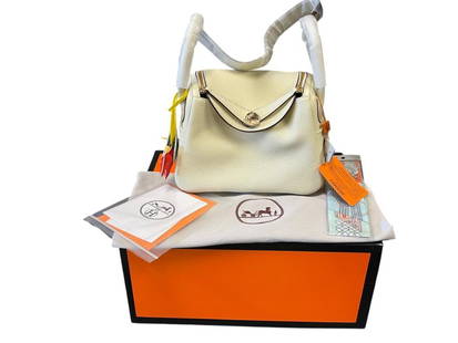 MARKED "HERMES" LINDY 26 NATA PEBBLED WHITE DESIGNER BAG WITH HORSE CHARMS AND HANDKERCHIEF: "HERMES" LINDY 26 NATA DESIGNER BAG WITH ORIGINAL BOX, DUST COVER, HORSE CHARMS, AND HANDKERCHIEF, NOT AUTHENTICATED, NEW CONDITION 10" L
